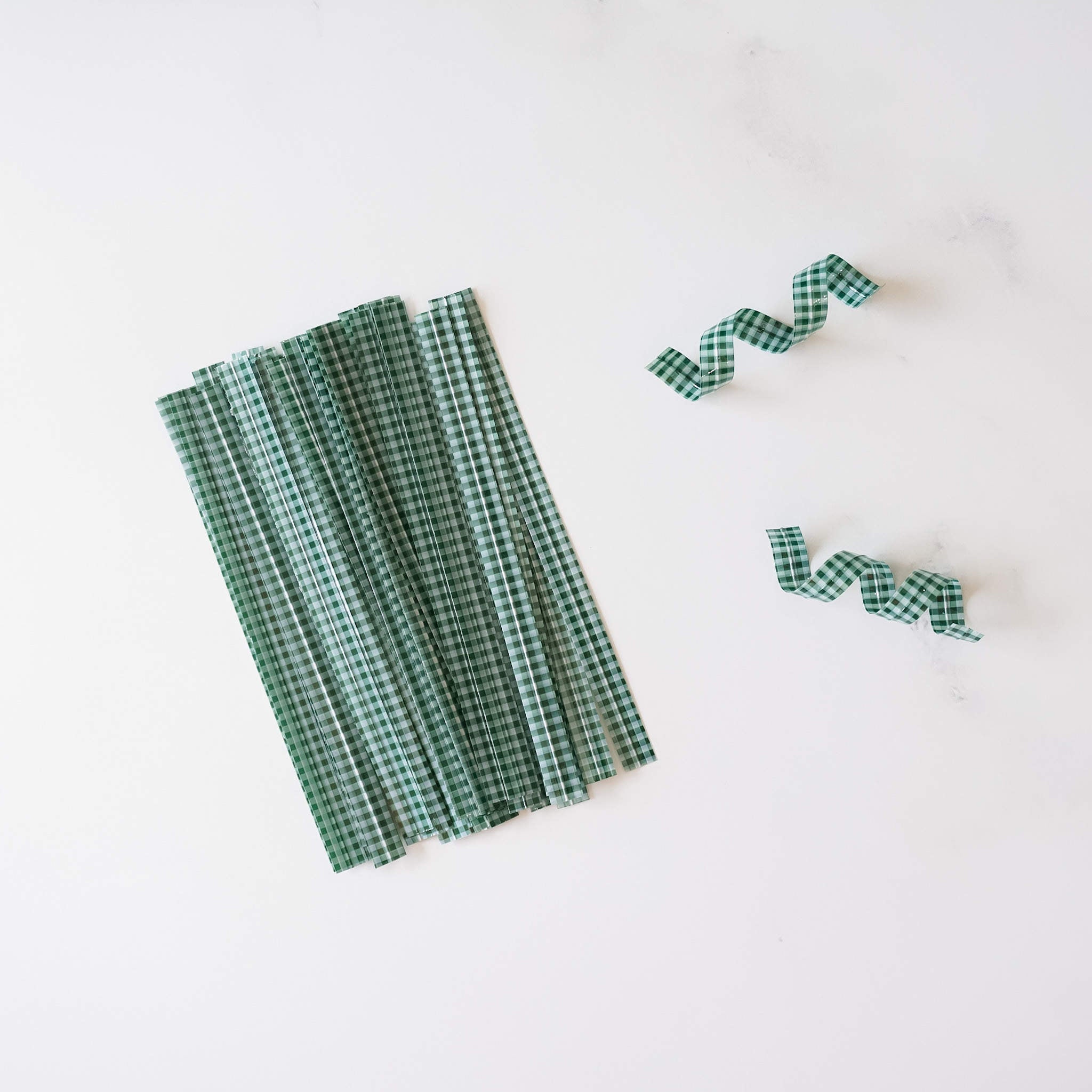 Dark green gingham check twist ties arranged on a white surface.