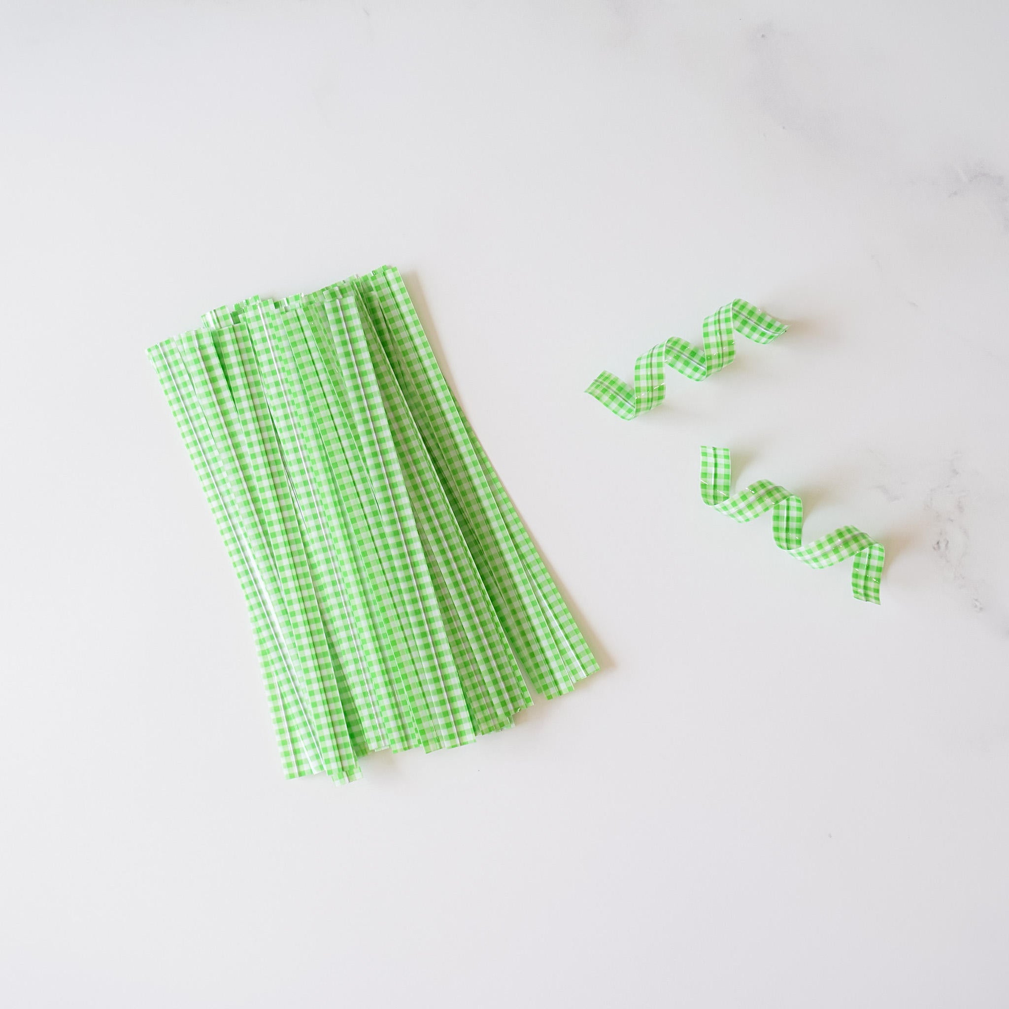 Light green gingham check twist ties arranged on a white surface.