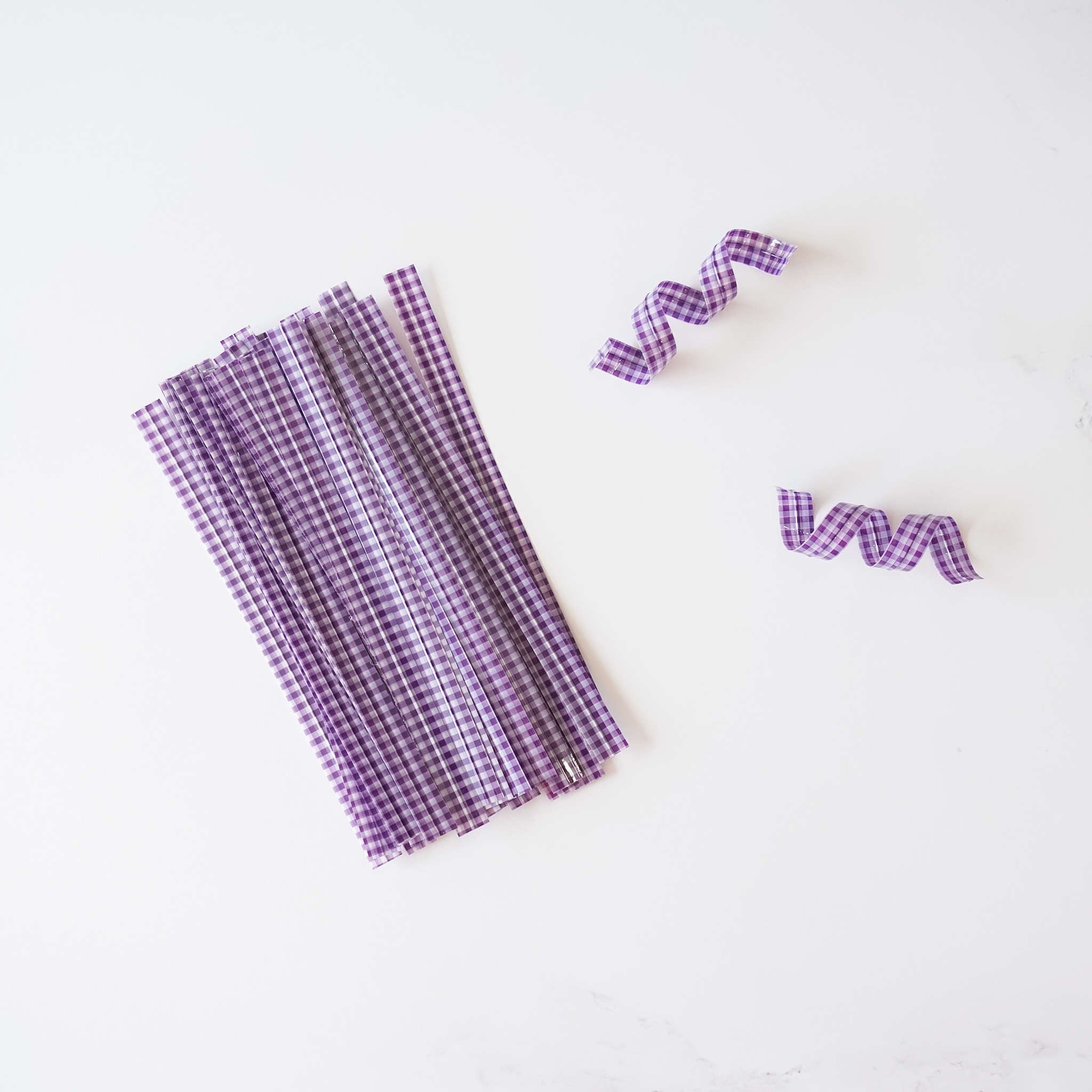Purple gingham check twist ties arranged on a white surface.