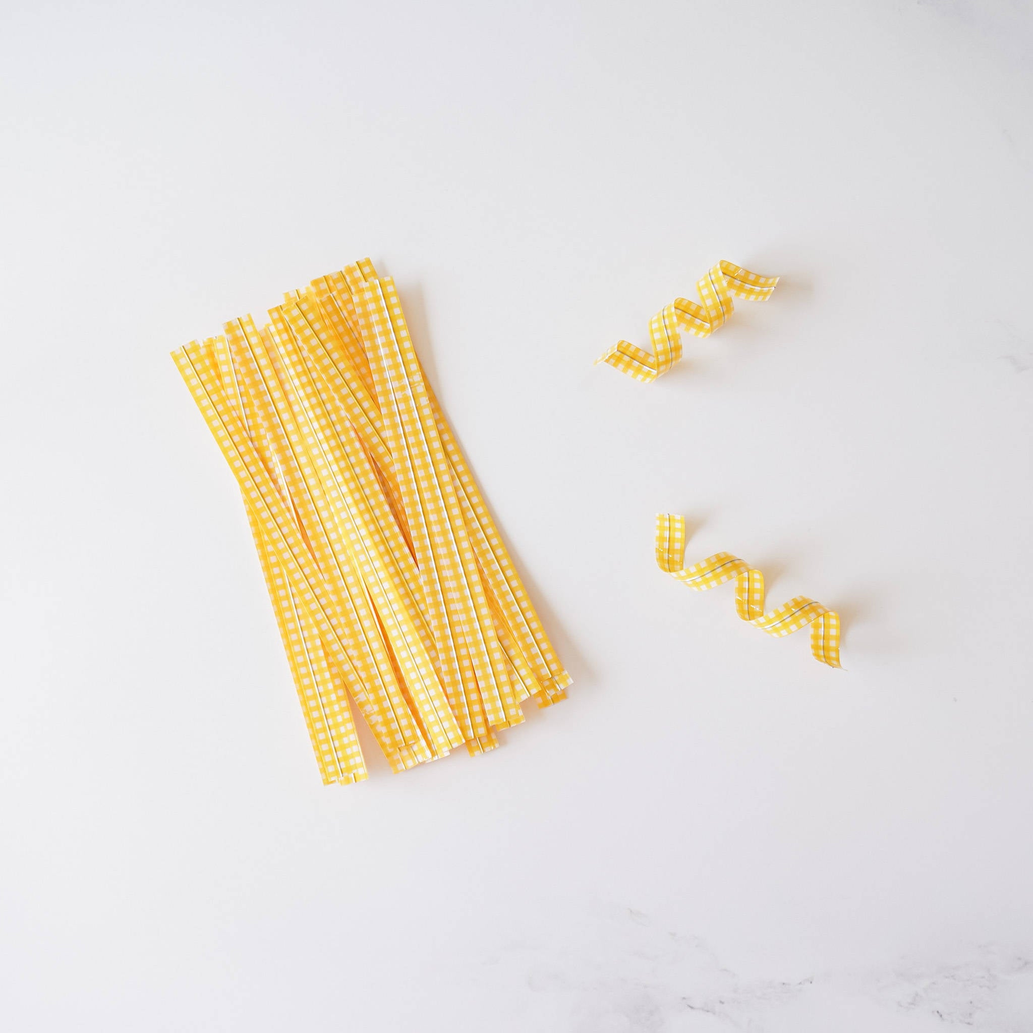 Yellow gingham check twist ties arranged on a white surface.