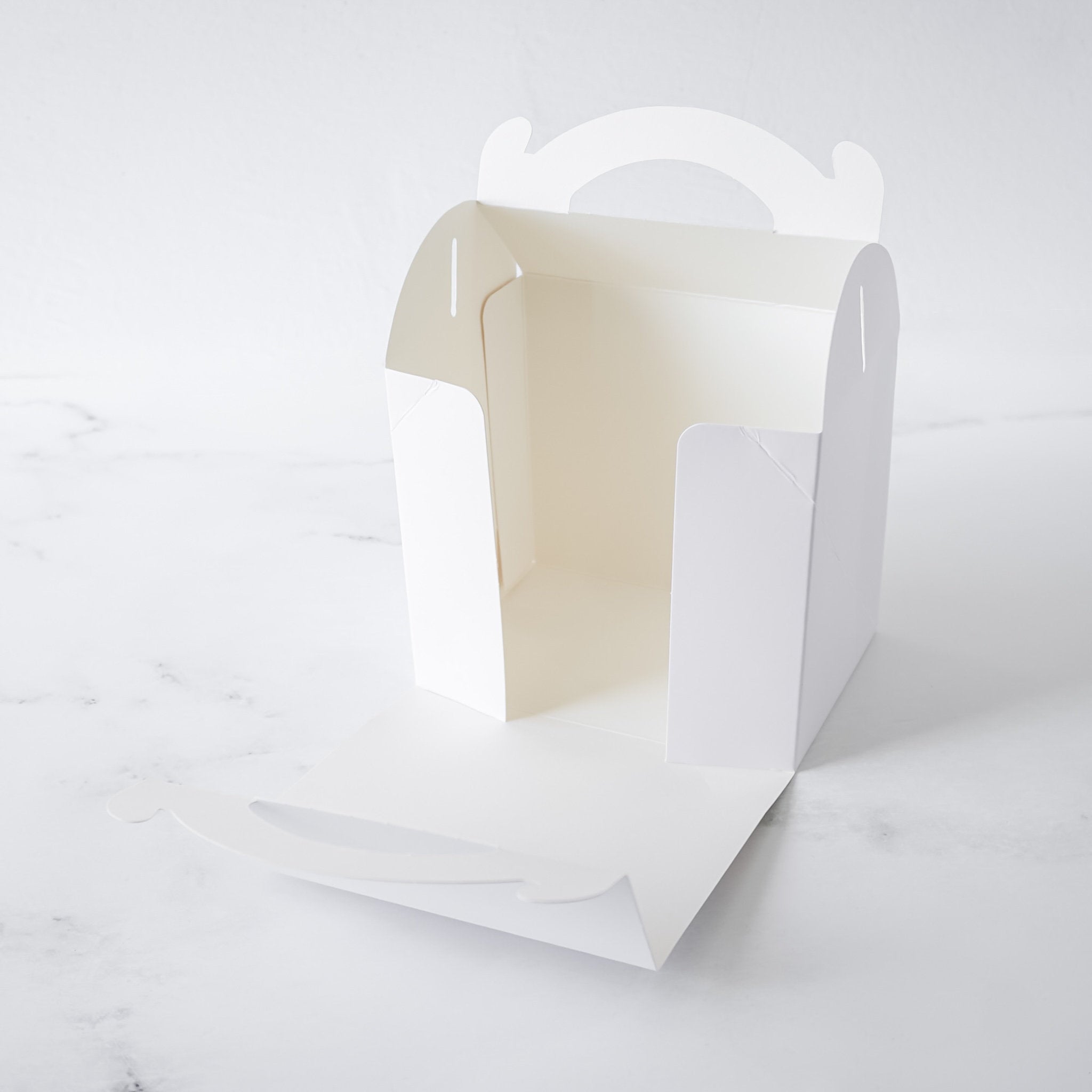 White paper bakery box with a white interior on a light gray background
