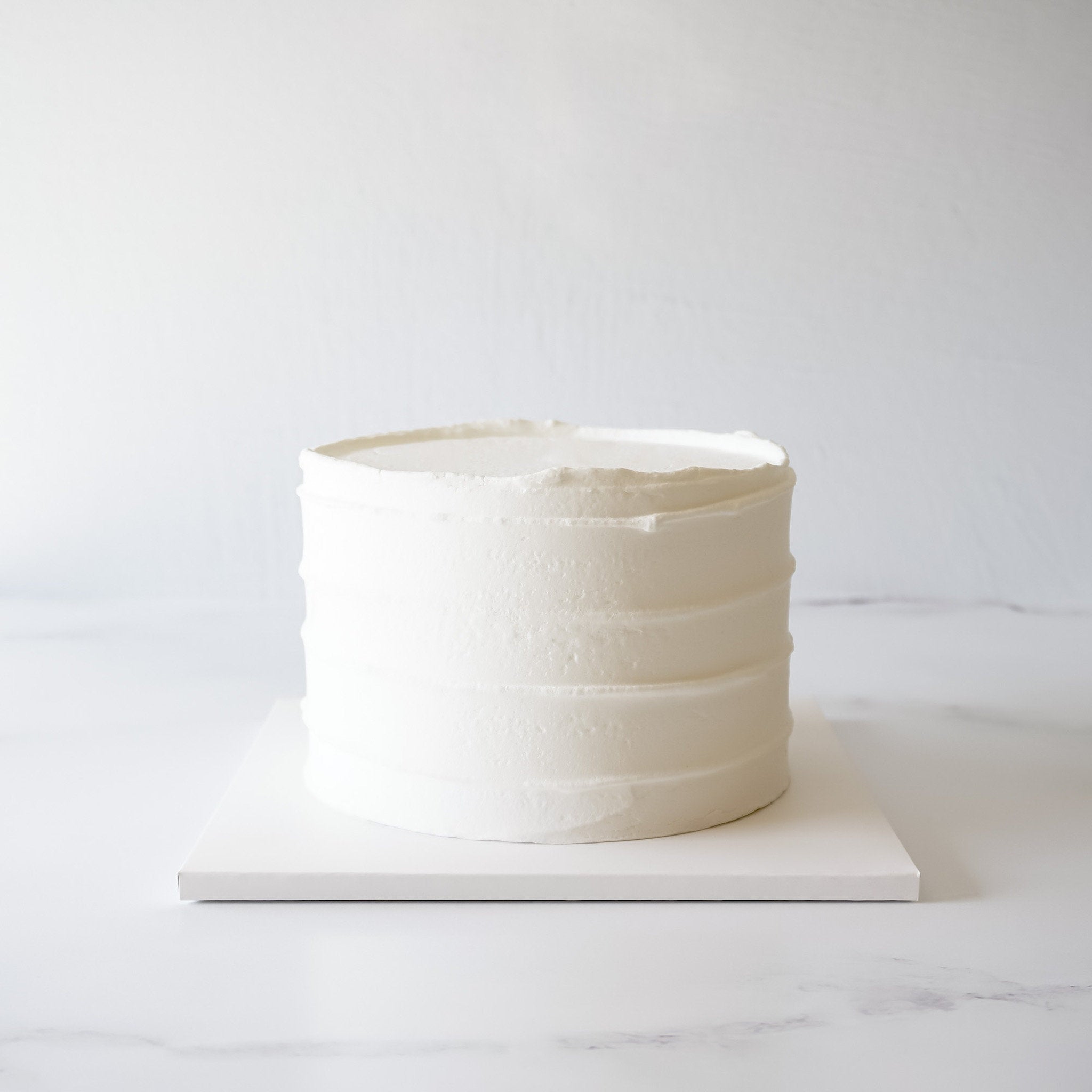 A cake presented on a white square cake board with a matte finish.