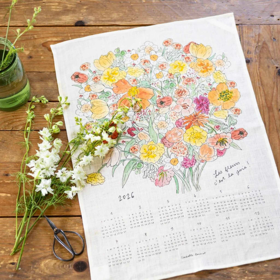 Floral design on a calendar cloth with flowers and scissors on a wooden surface