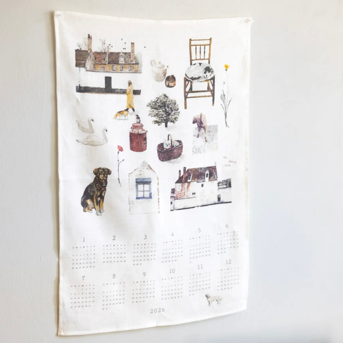 Calendar cloth on a white wall with illustrations of houses, animals, and objects.
