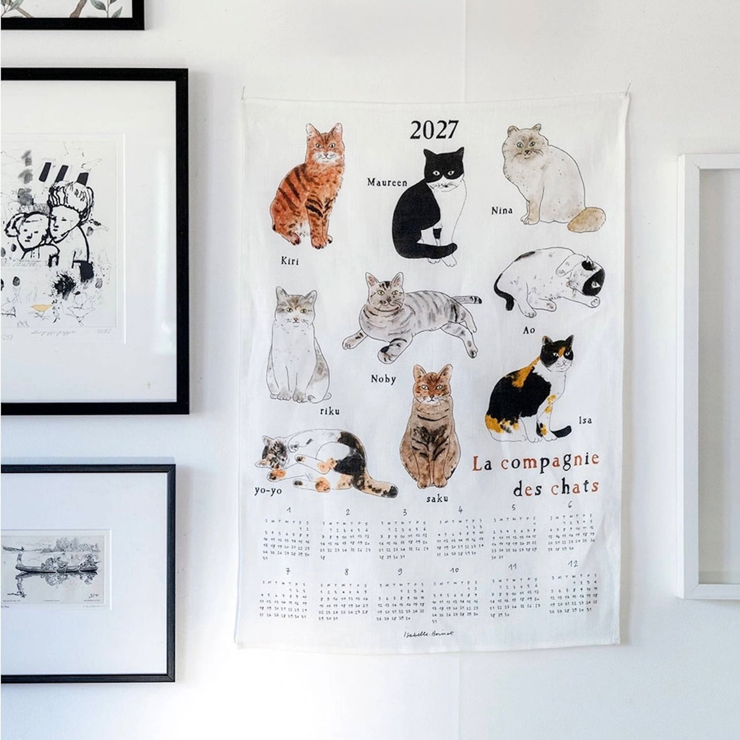 A white linen fabric wall calendar featuring illustrated cats and the French text &