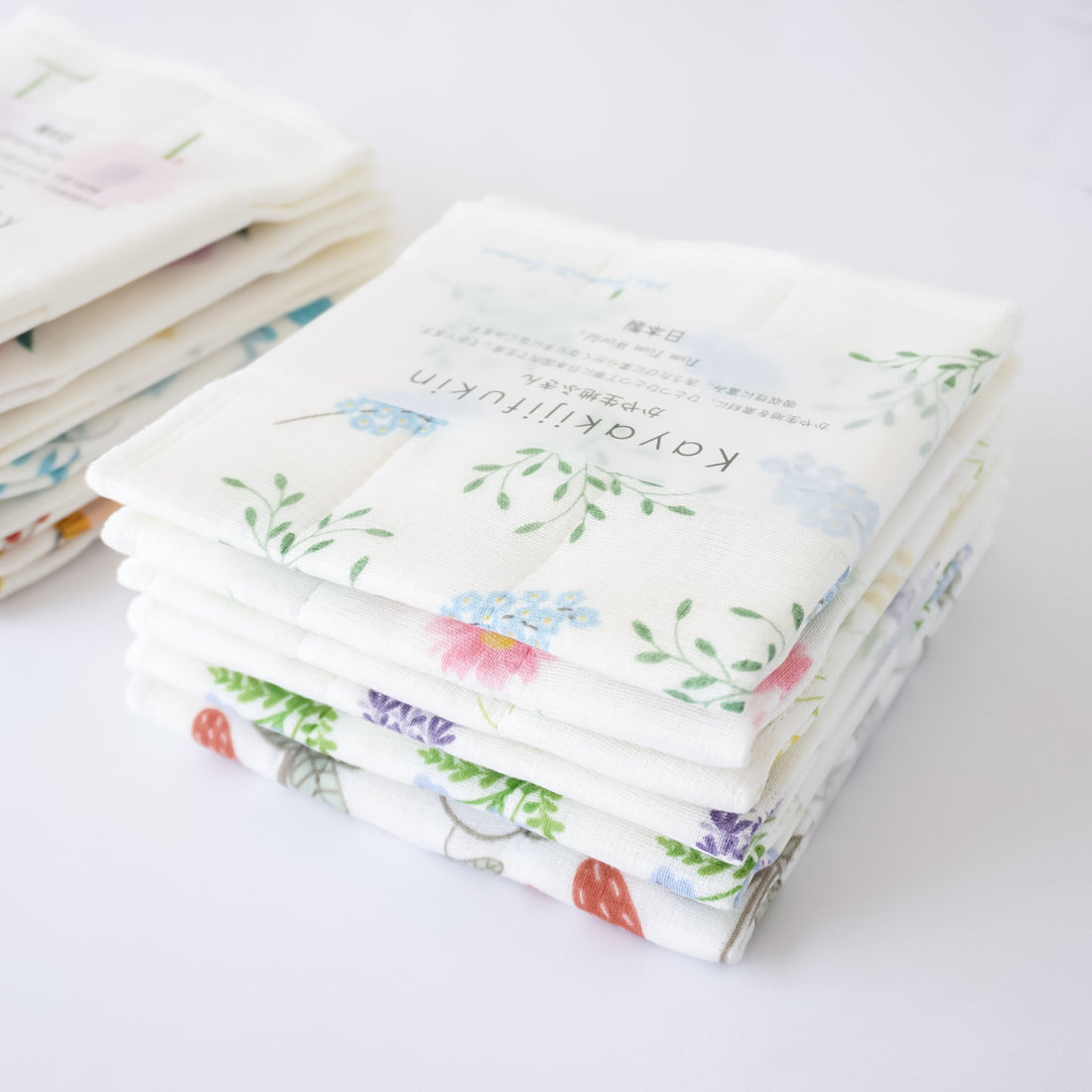A stack of folded Japanese dishcloths with floral and other patterns, wrapped in an obi-style finish.