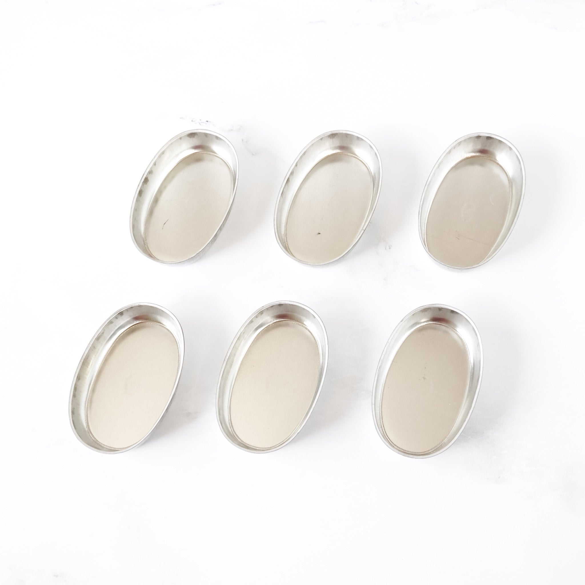 Set of silver oval financier pans on a white background