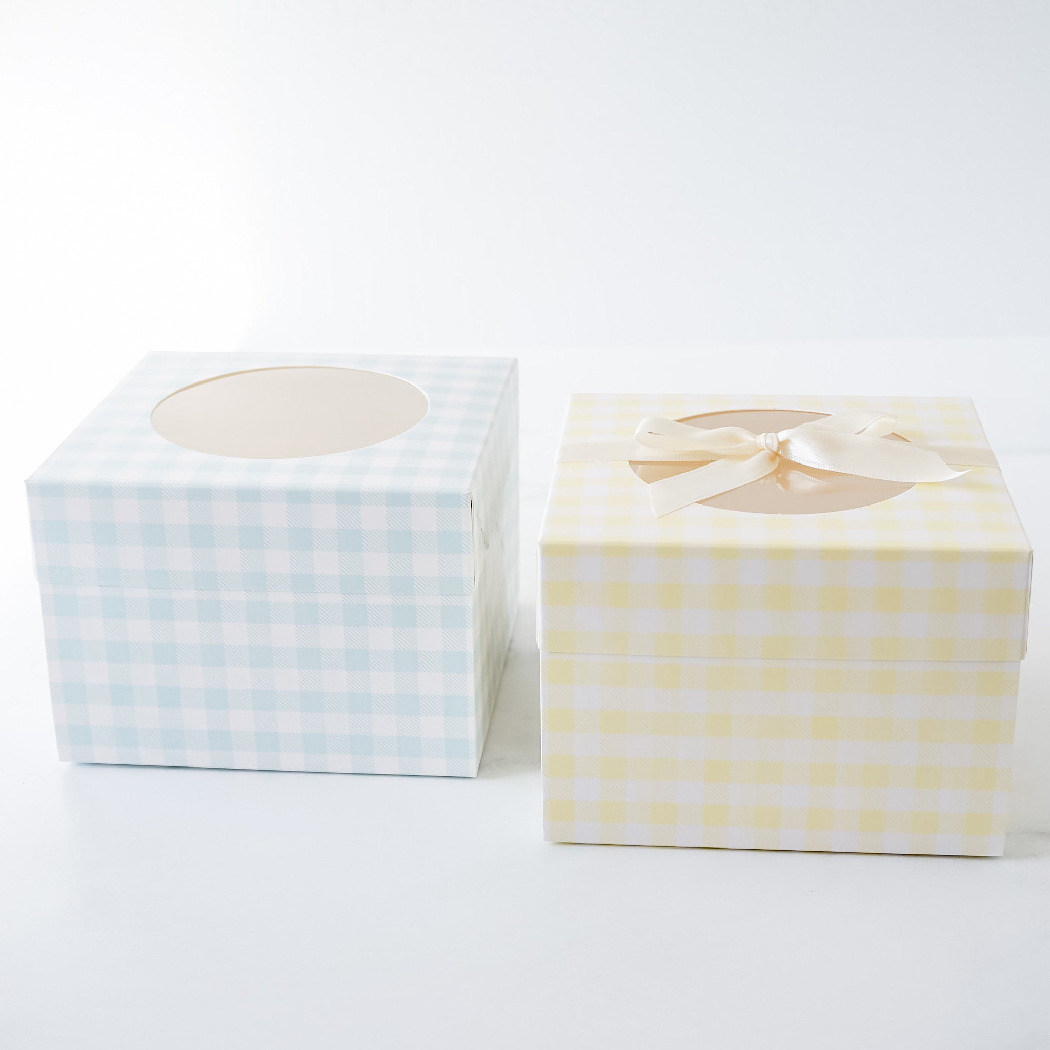 two square gift boxes with a window and a ribbon. The boxes are in yellow, white, and blue gingham patterns.