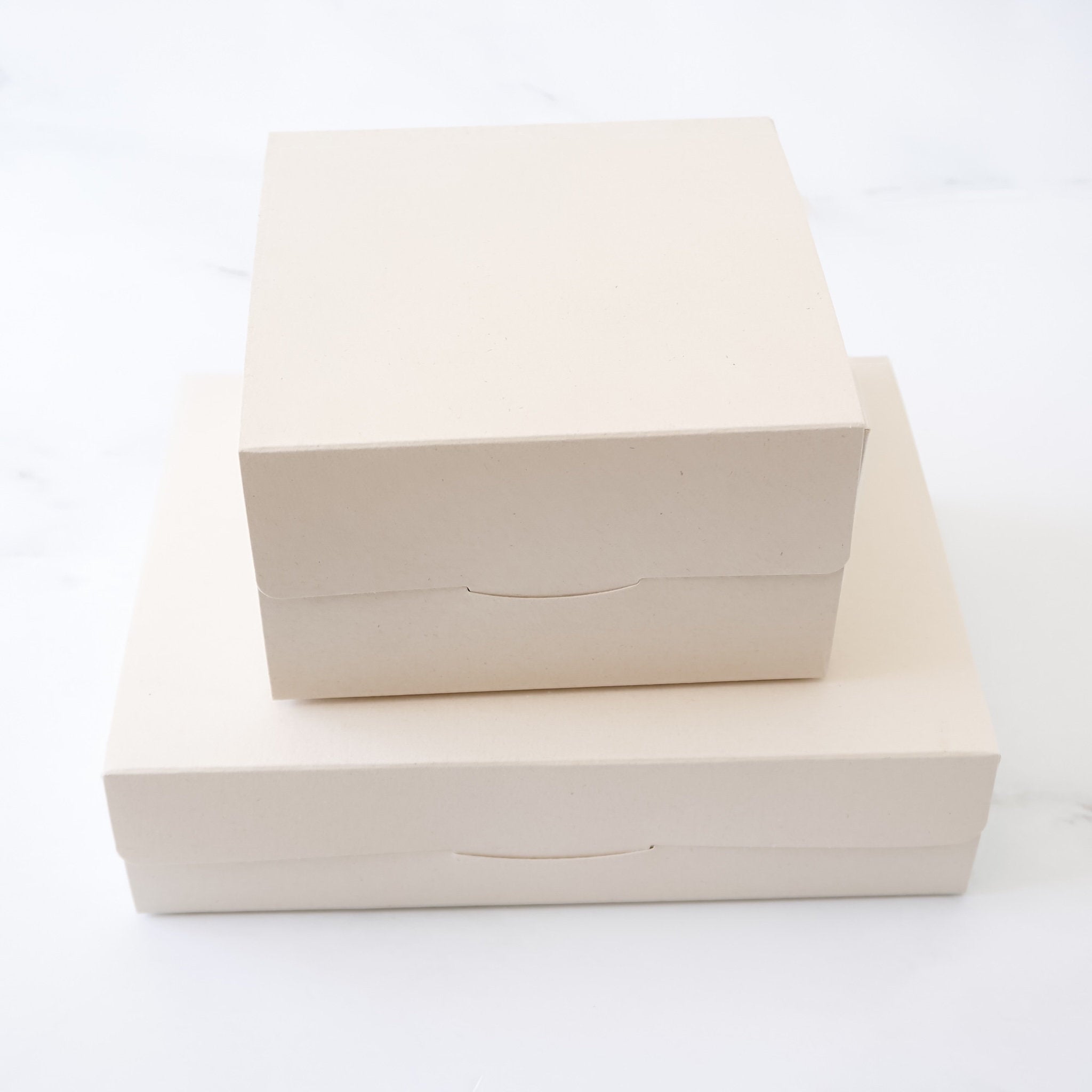 Two beige bakery boxes stacked on a white background