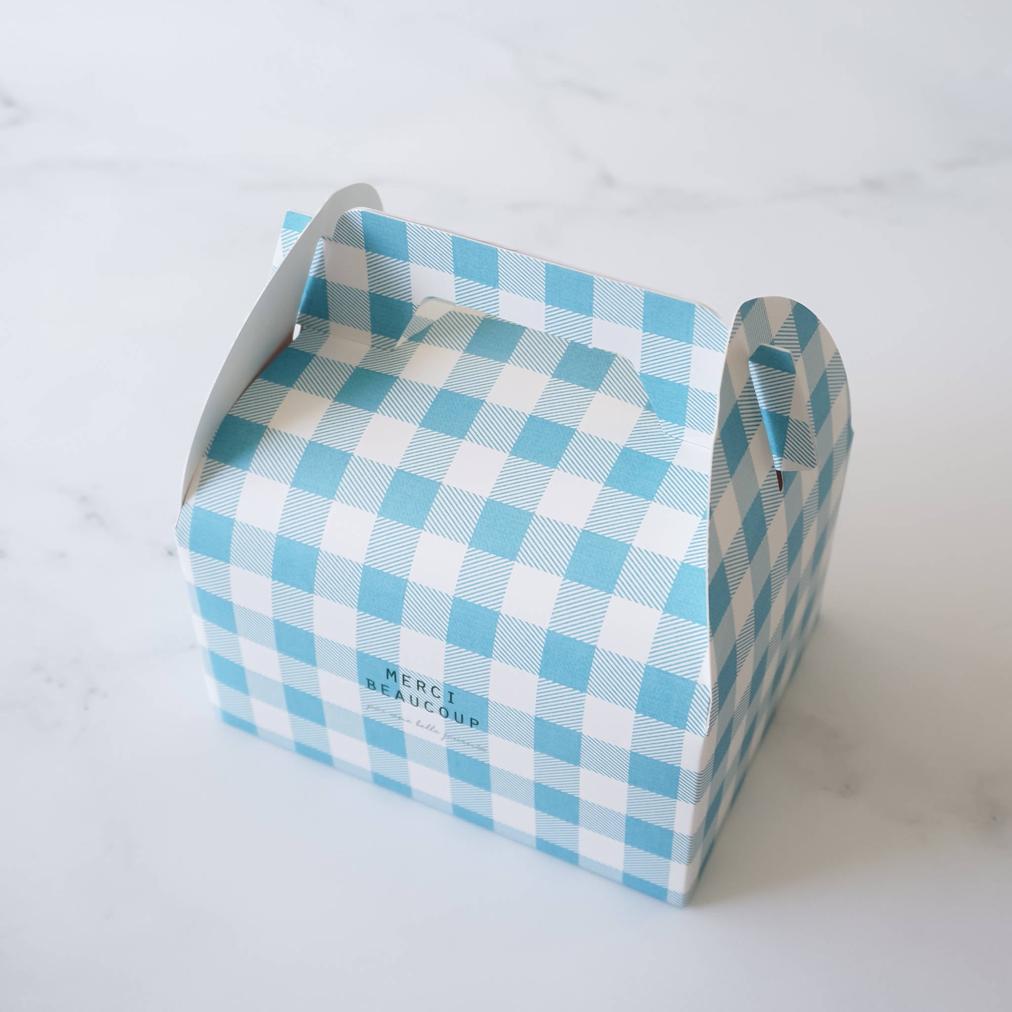 A blue and white gingham gift box with a handle. The box has the words &