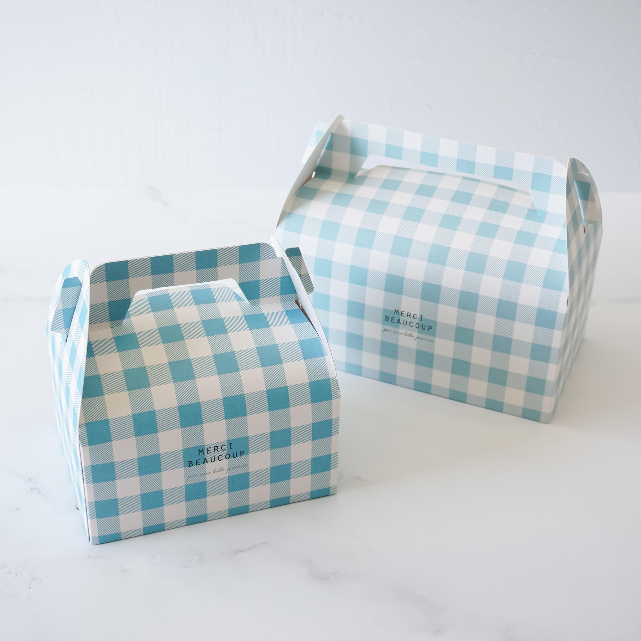 Two blue gingham gable boxes with a checkered pattern, designed for packaging bakery items.