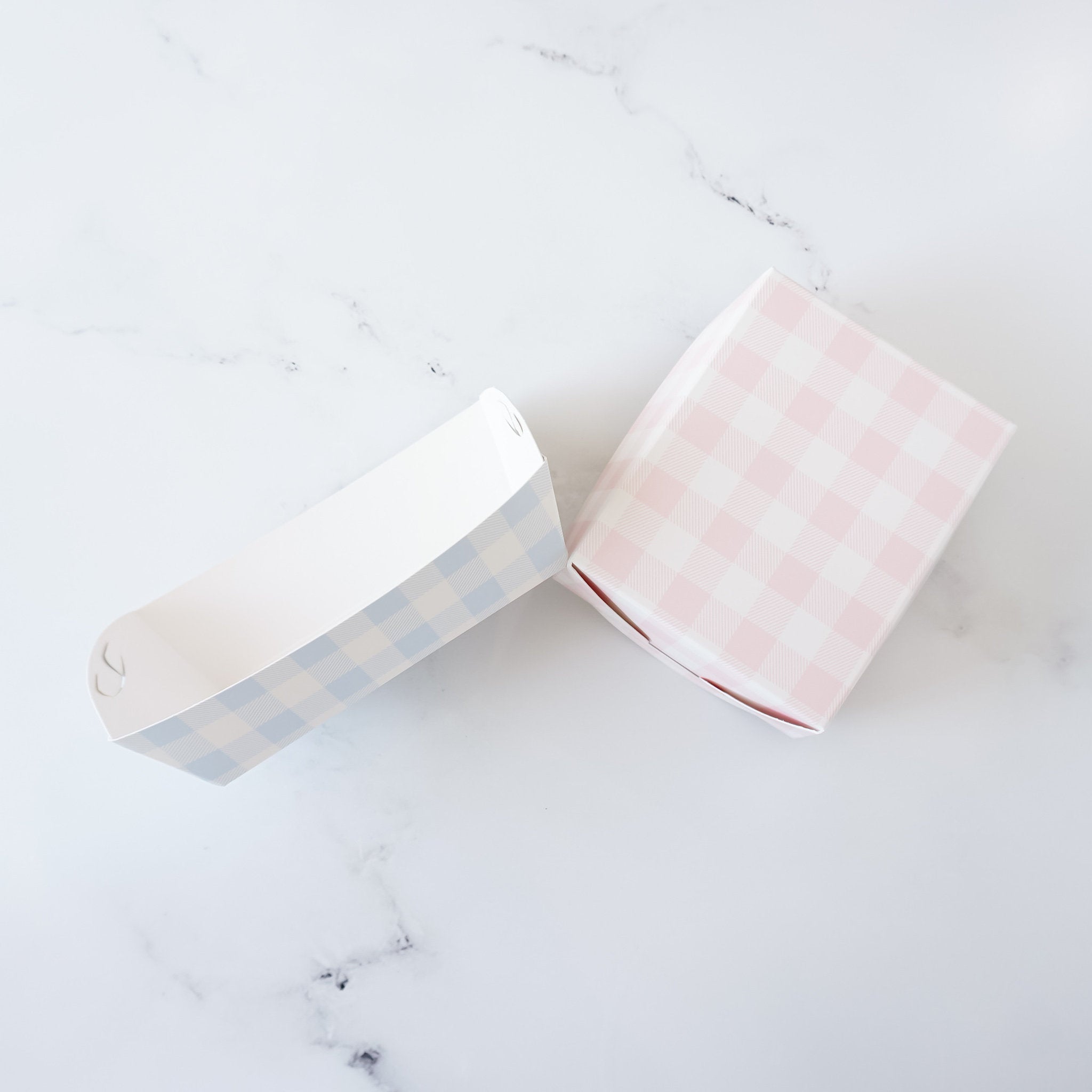 Two food boxes, one blue and one pink, with a checkered pattern. The boxes are made of paper and are designed for takeout food.
