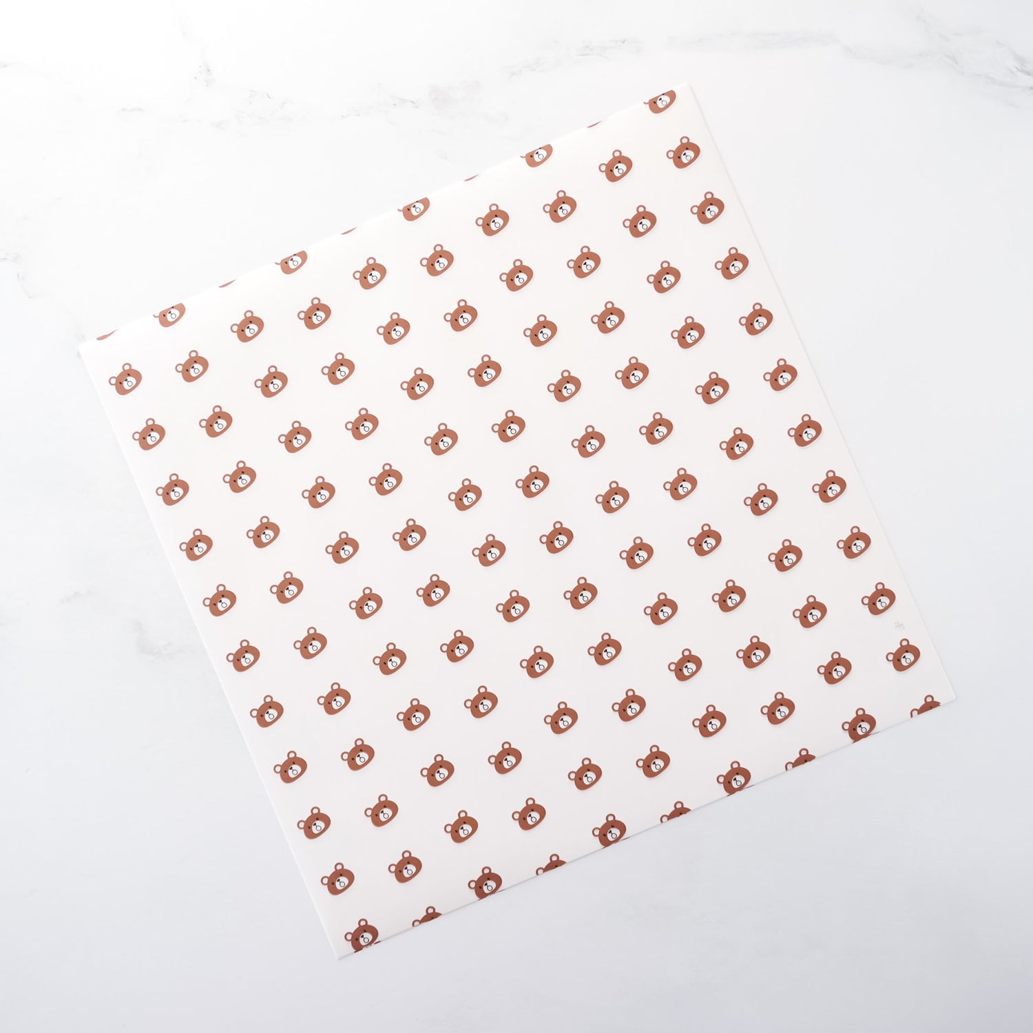 White parchment paper with a pattern of small brown bear shapes arranged in a grid on a white background