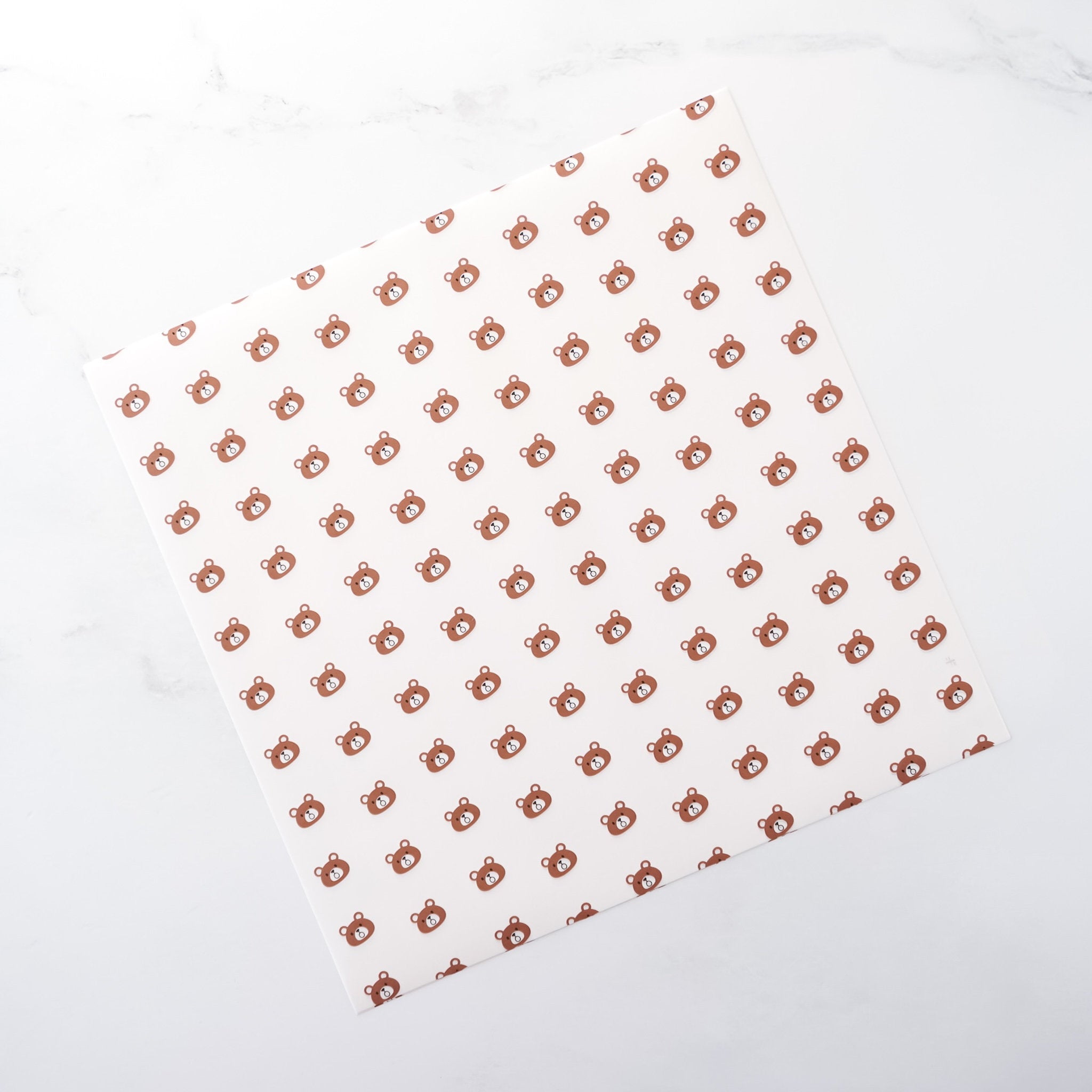 White parchment paper with a pattern of small brown bear shapes arranged in a grid on a white background