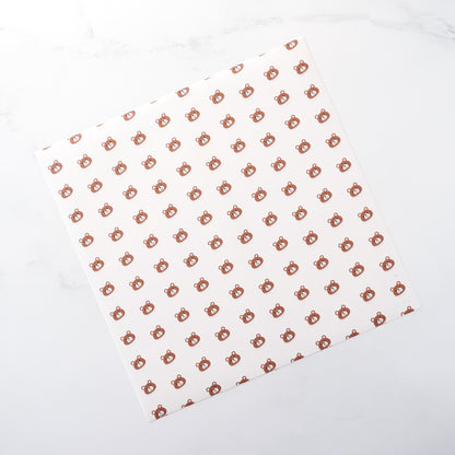 White parchment paper with a pattern of small brown bear shapes arranged in a grid on a white background