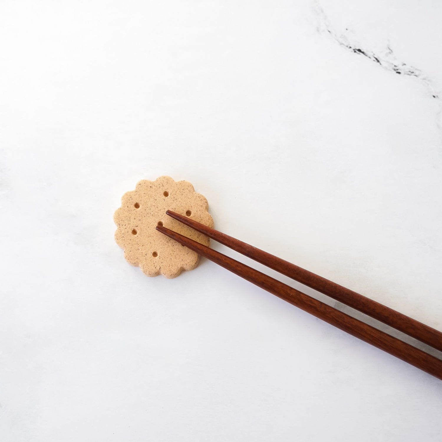 Chopsticks resting on a round cookie on a white surface