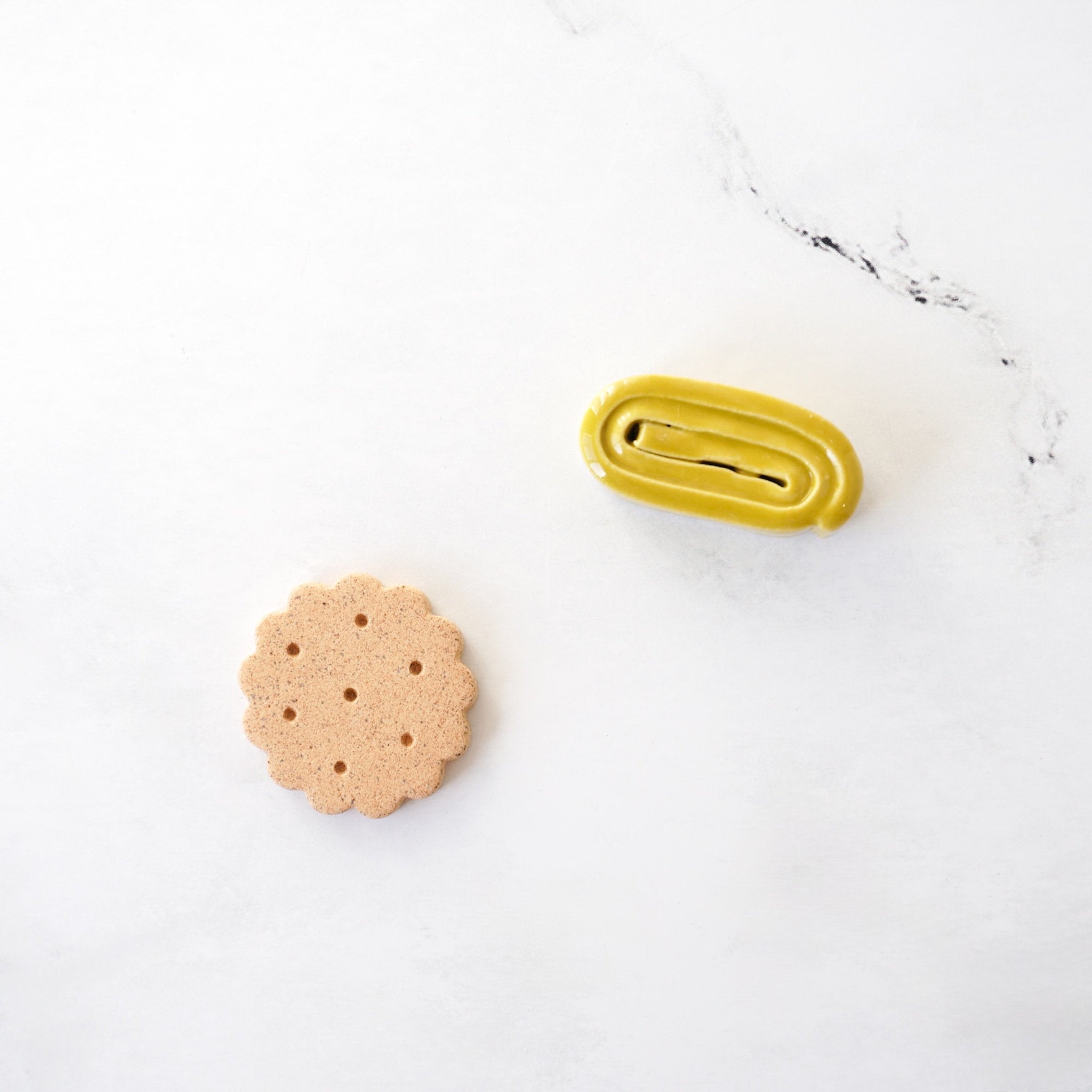 Round cracker-like cookie and yellow tamagoyaki chopstick rests on a white surface