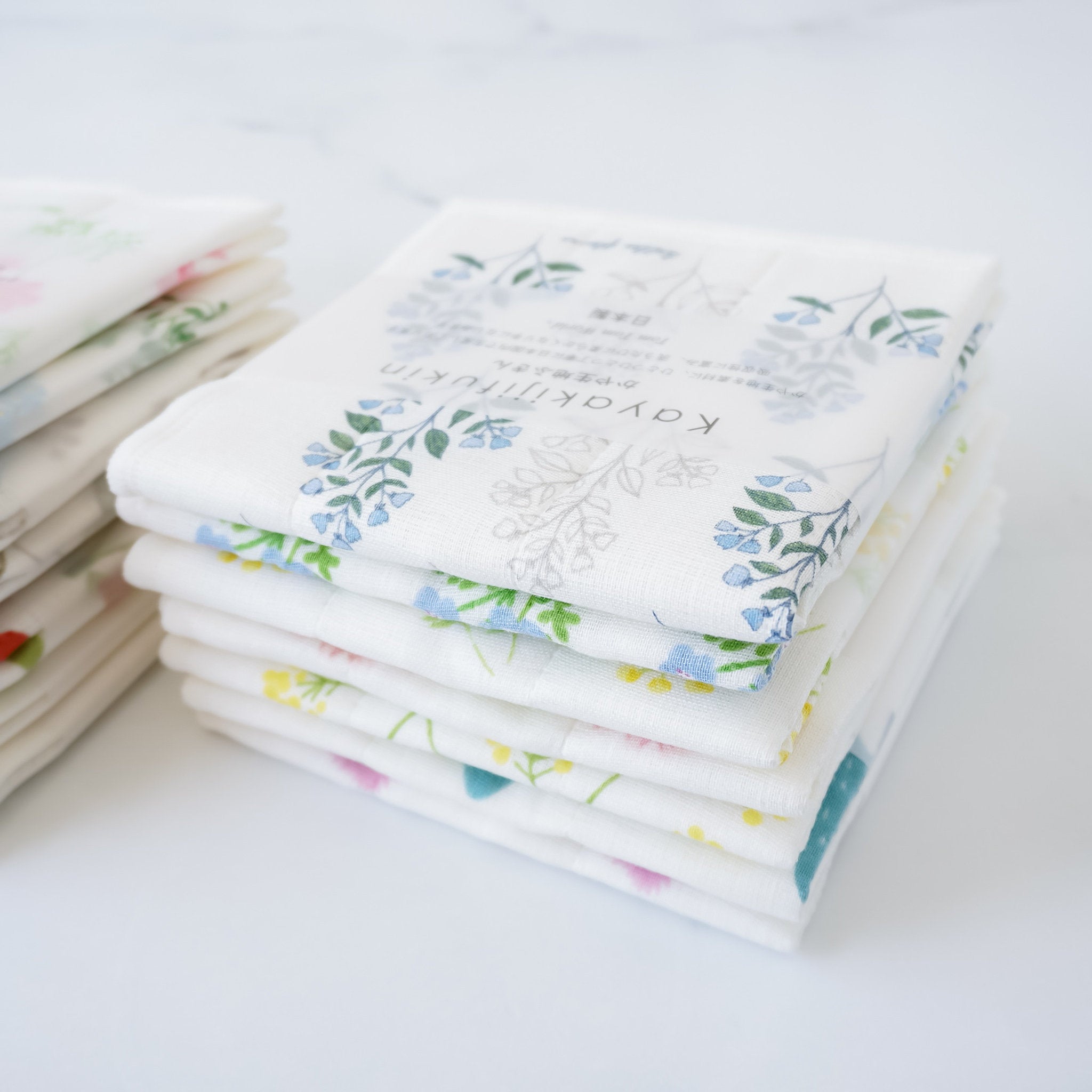 A stack of folded Japanese dishcloths with floral and other patterns, wrapped in an obi-style finish.