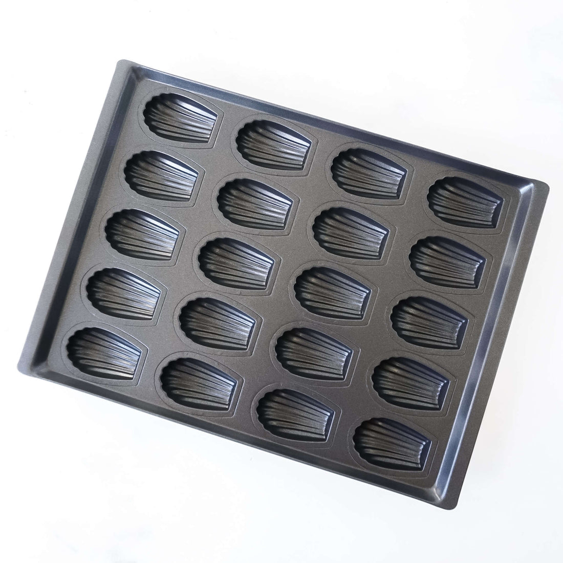 Metallic madeleine cake mold on a white background