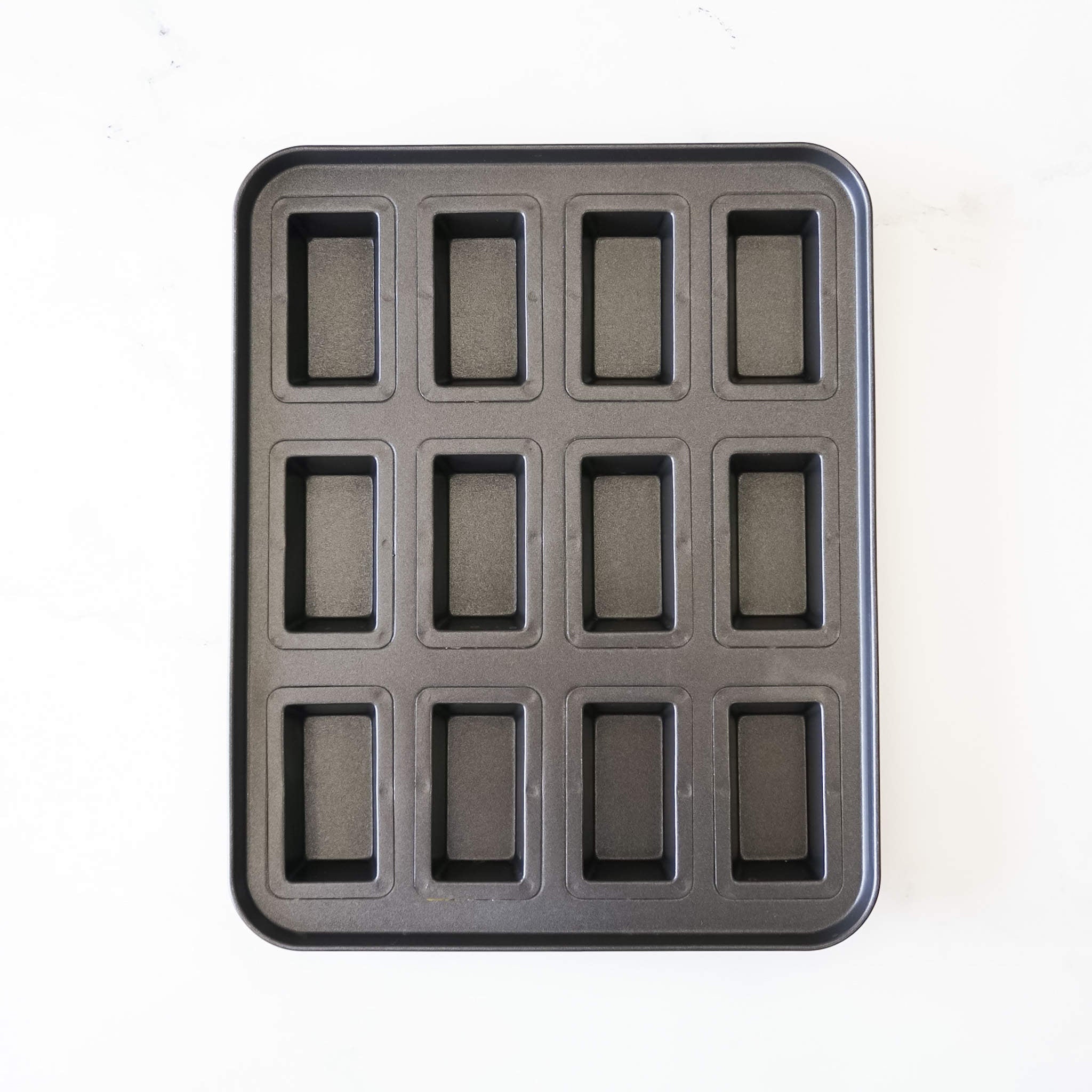 A financier cake pan with 12 cavity molds with a non-stick surface.