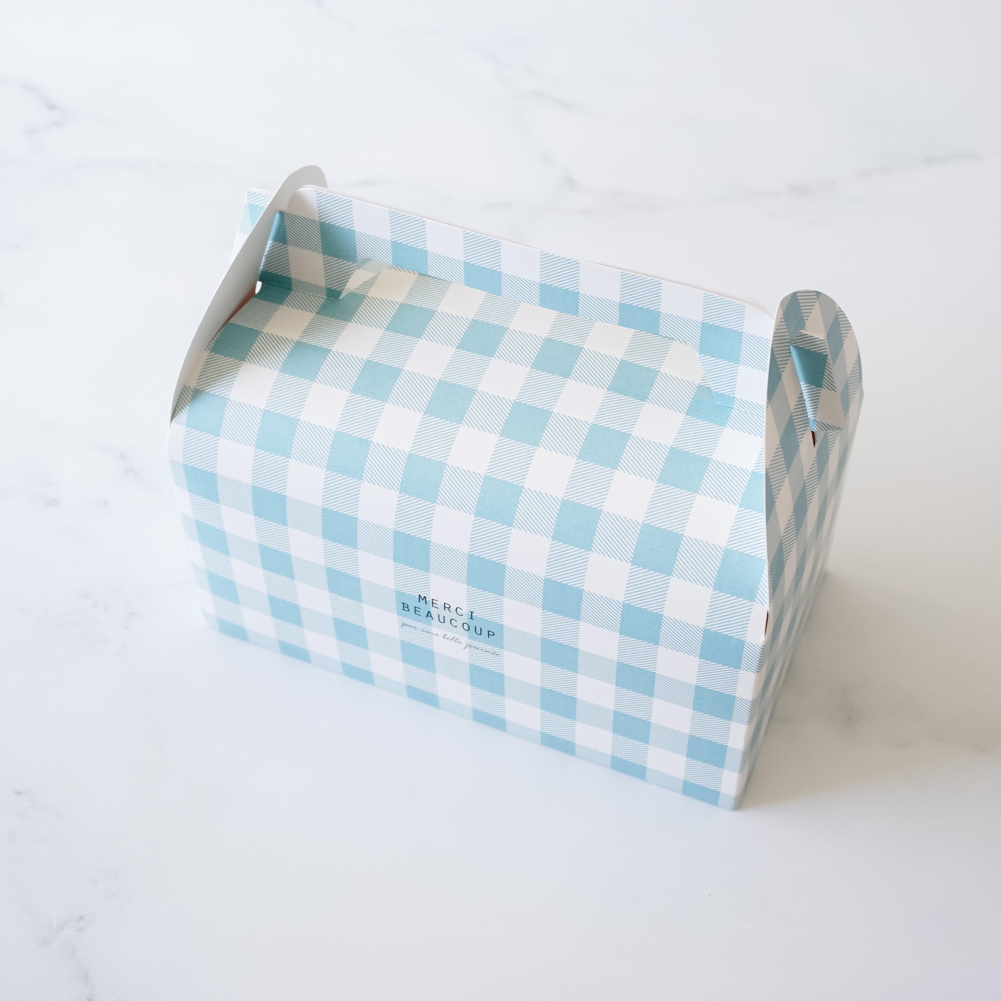 A blue and white gingham gift box with a handle. The box has the words &