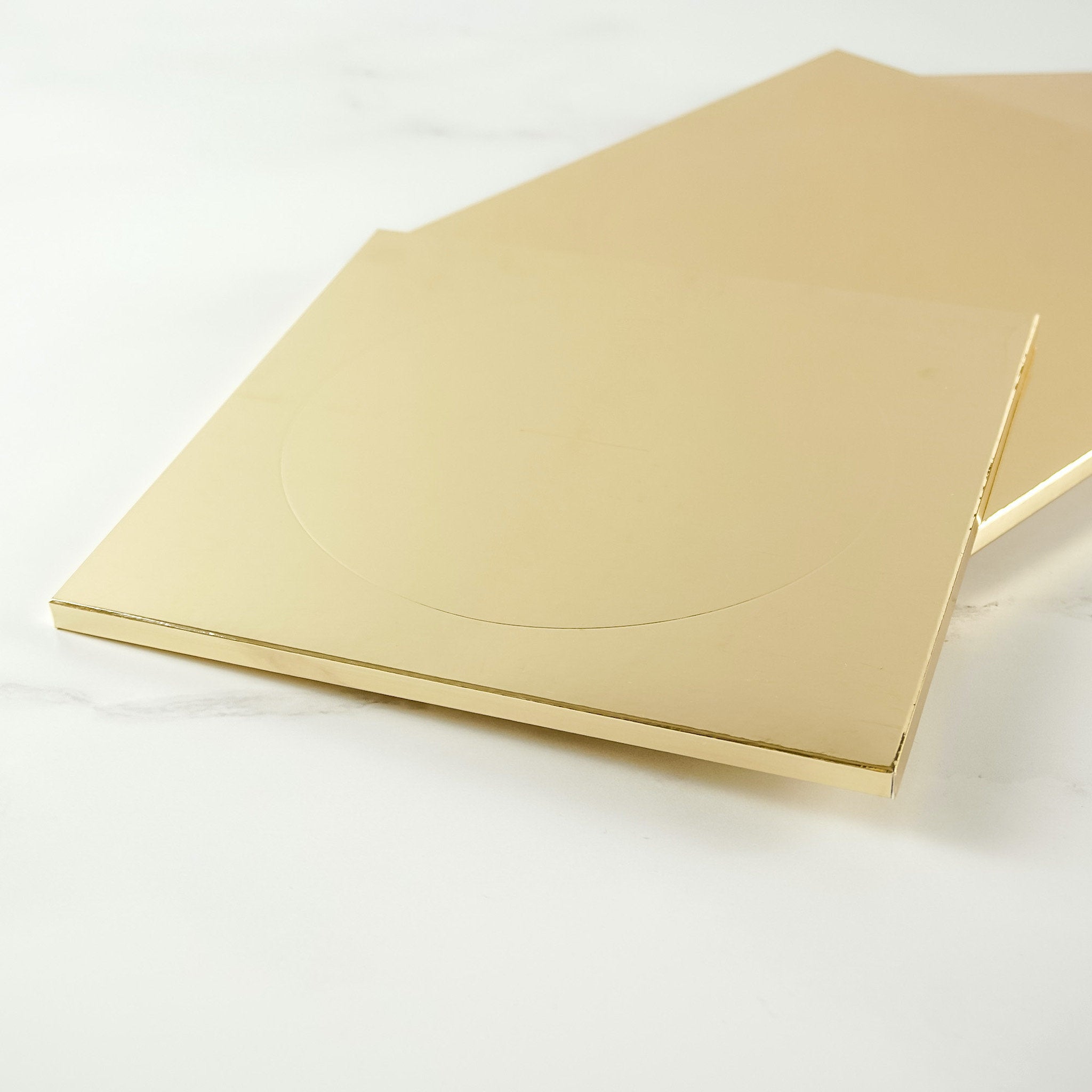 Two gold cake boards stacked on top of each other
