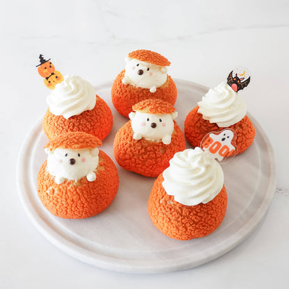 A set of Halloween cupcake toppers with three designs: a pumpkin, a ghost, and a bat, displayed on a plate.
