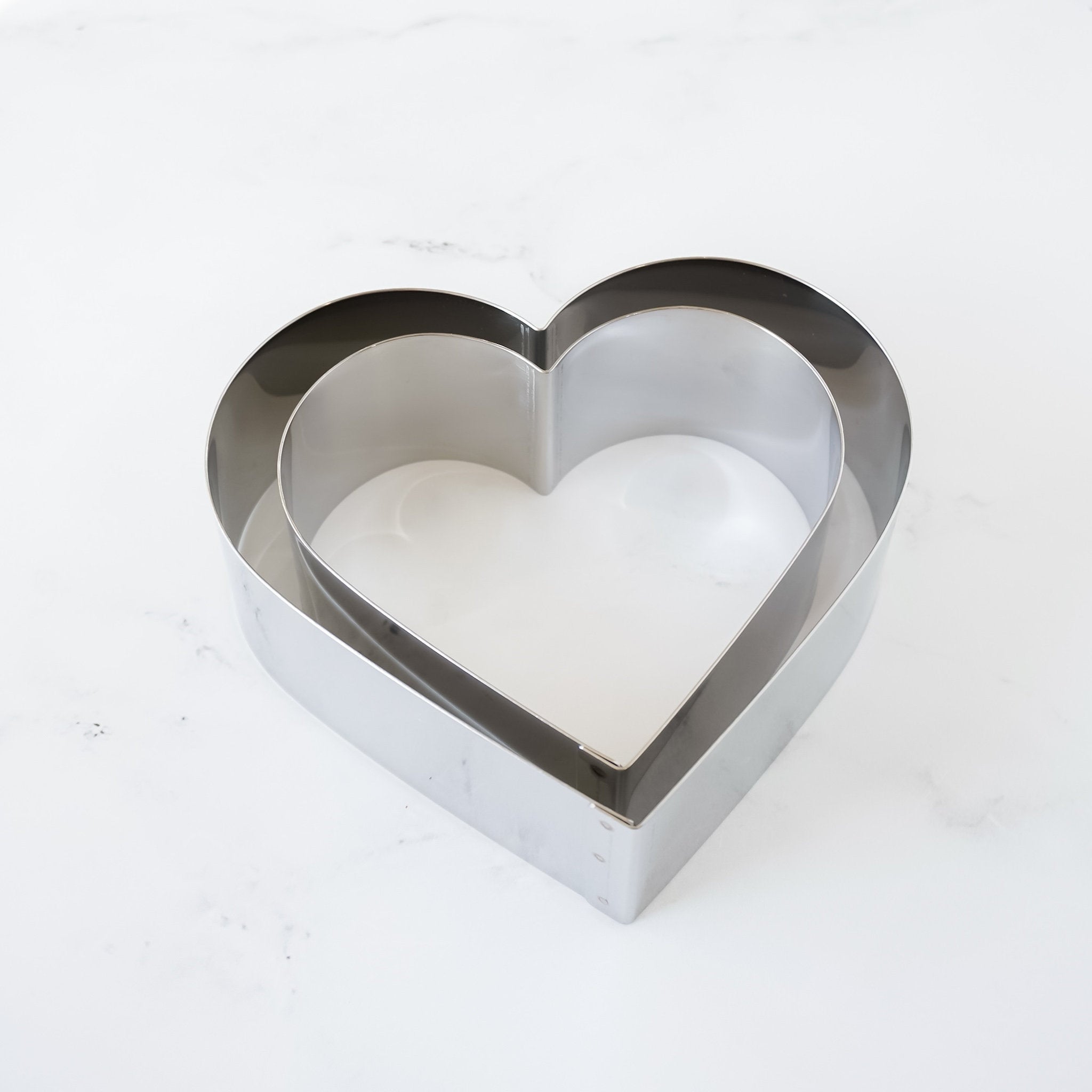Two silver heart-shaped cake rings, one nested inside the other.