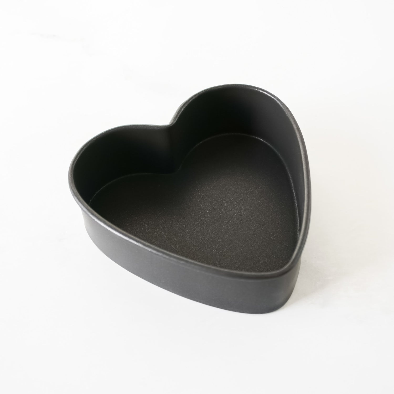 Heart-shaped black baking pan on a white background