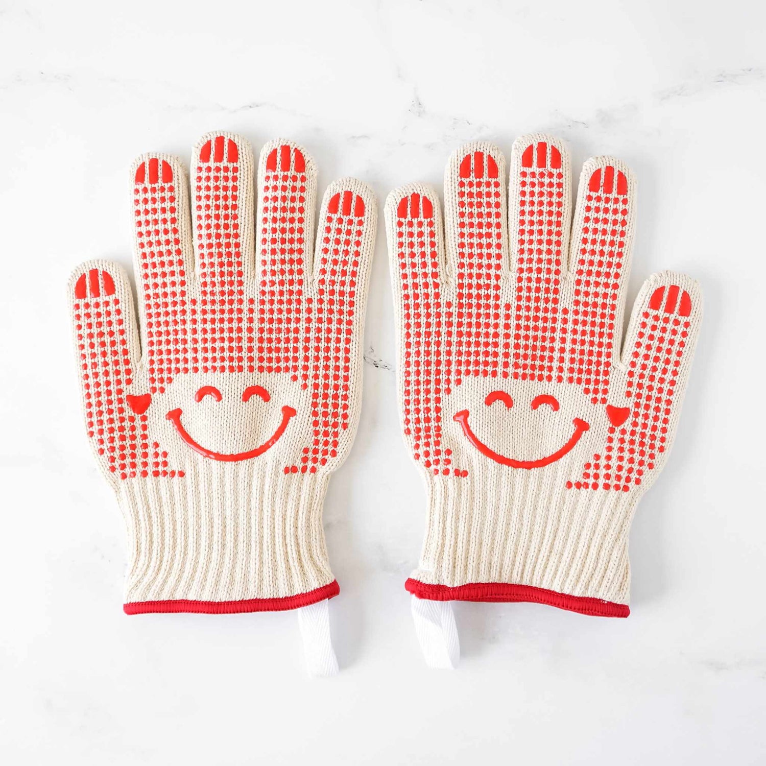 Pair of oven gloves with smiley face design on a white background
