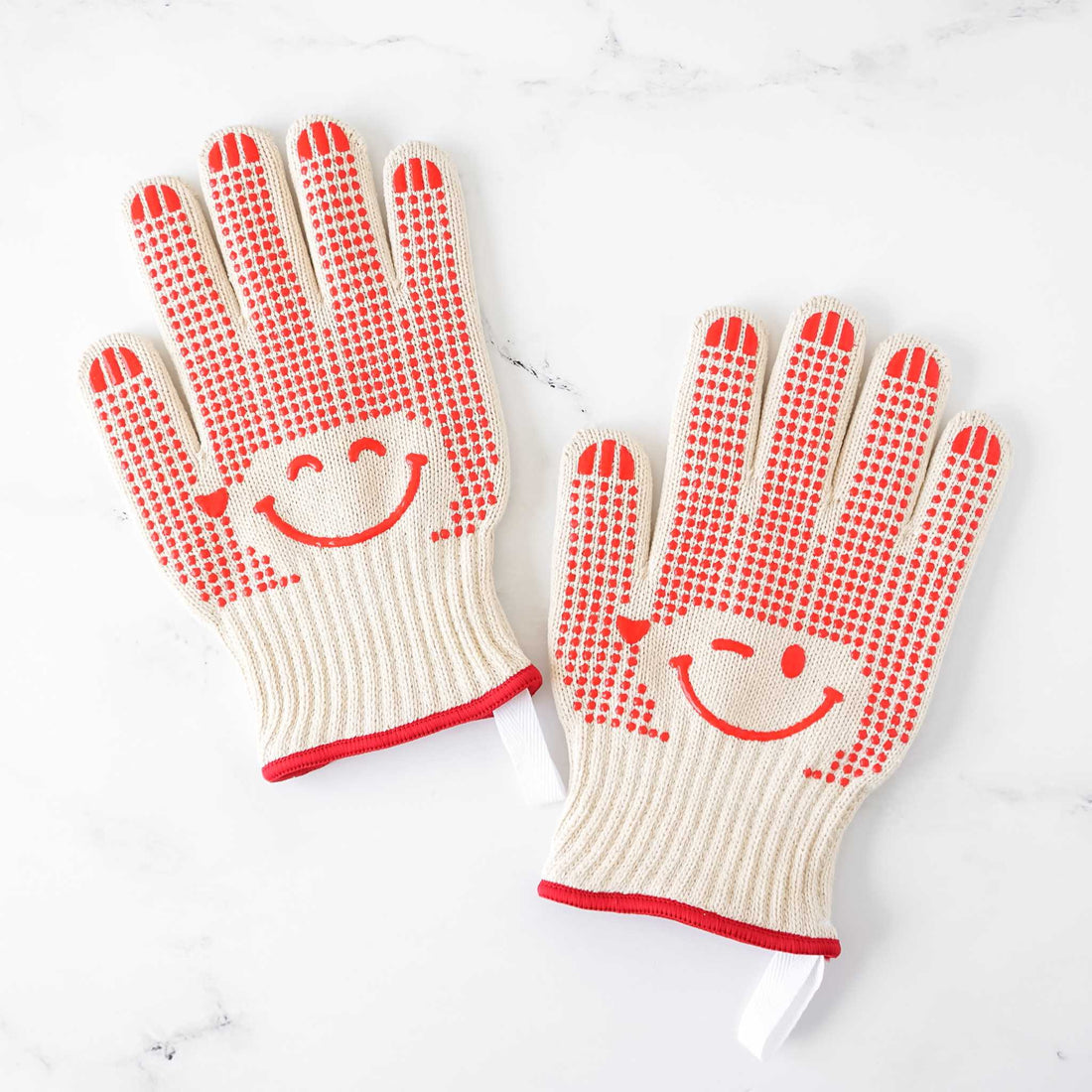 Pair of oven gloves with smiley face design on a white background