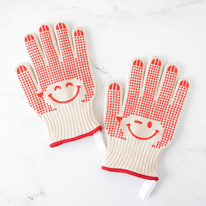 Pair of oven gloves with smiley face design on a white background