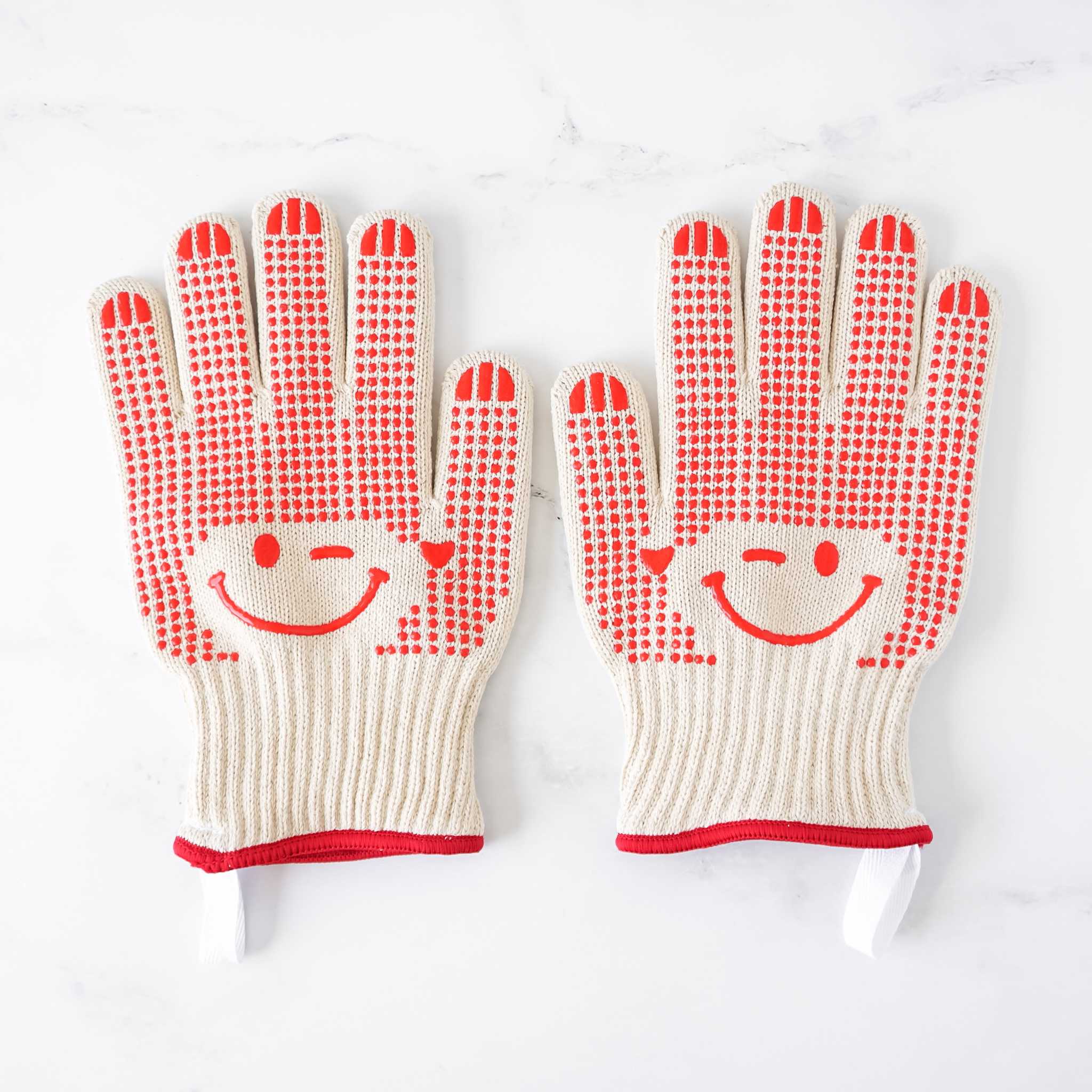 Pair of oven gloves with smiley face design on a white background