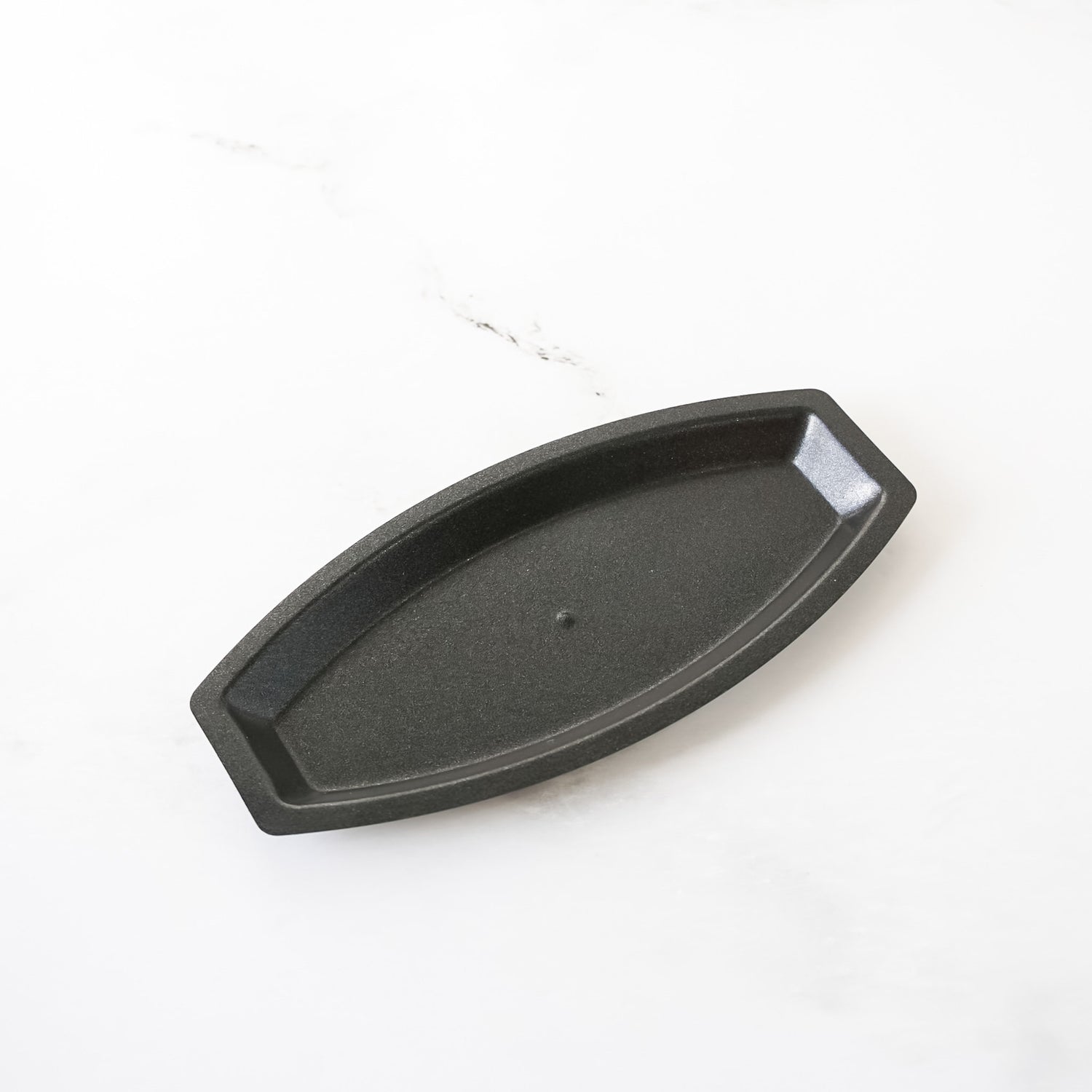 Black metal boat-shaped baking mold on a white background