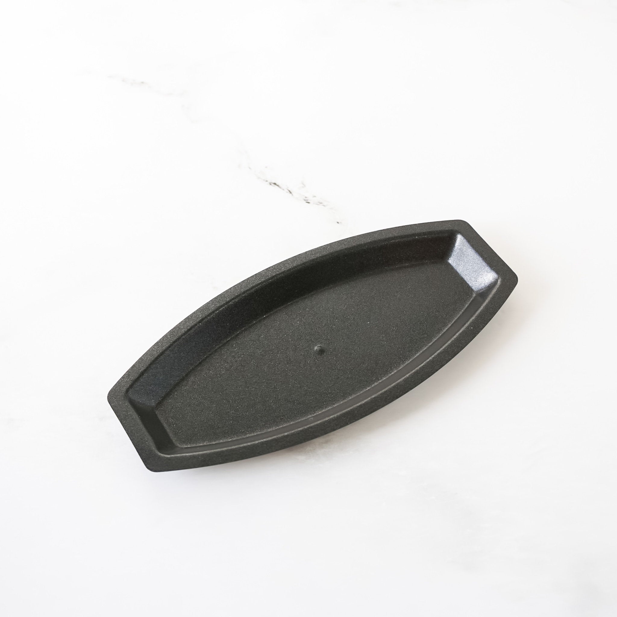 Black metal boat-shaped baking mold on a white background