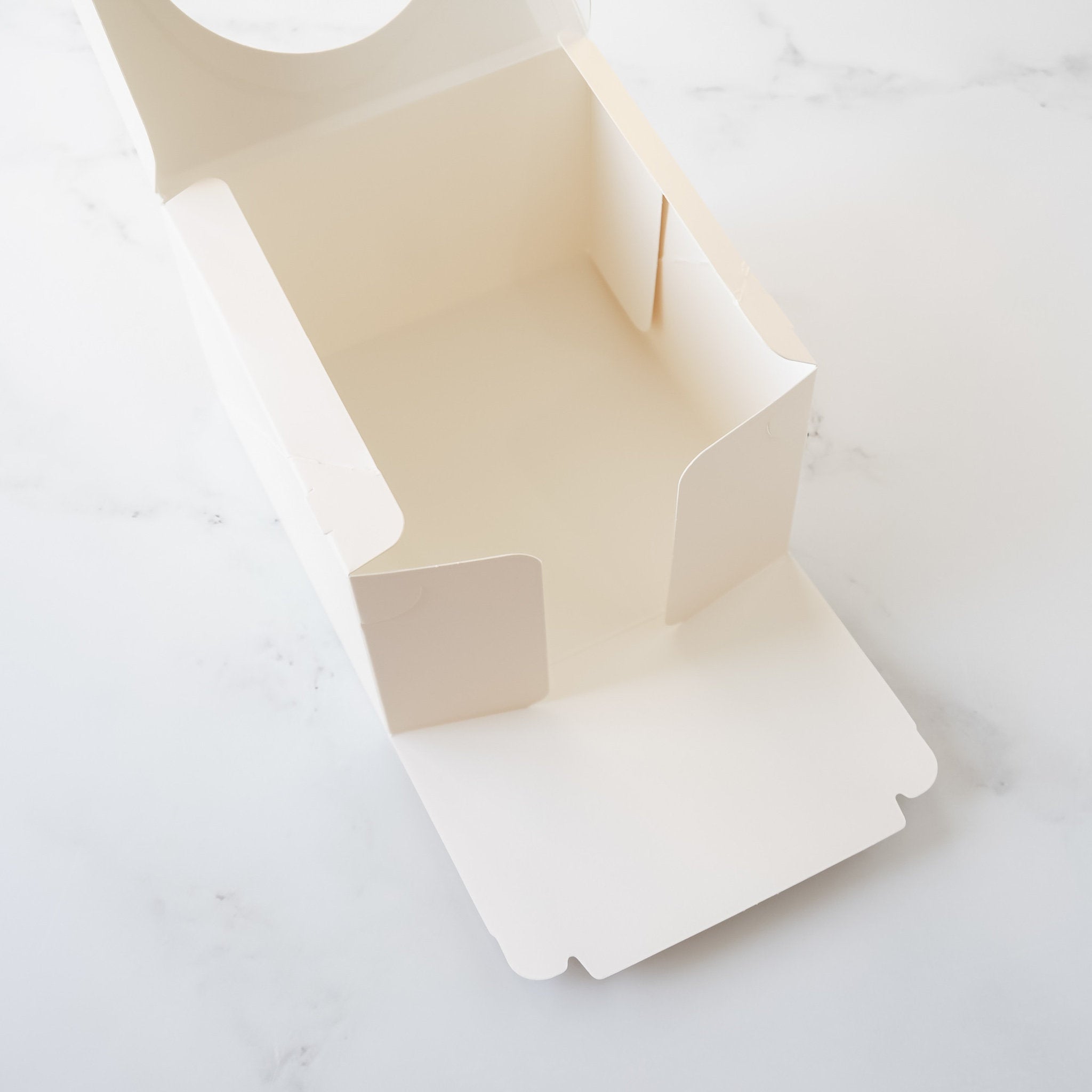 An ivory cardboard box with a hinged lid. The box is open and the lid is folded back. The box is empty and has a smooth, white interior.