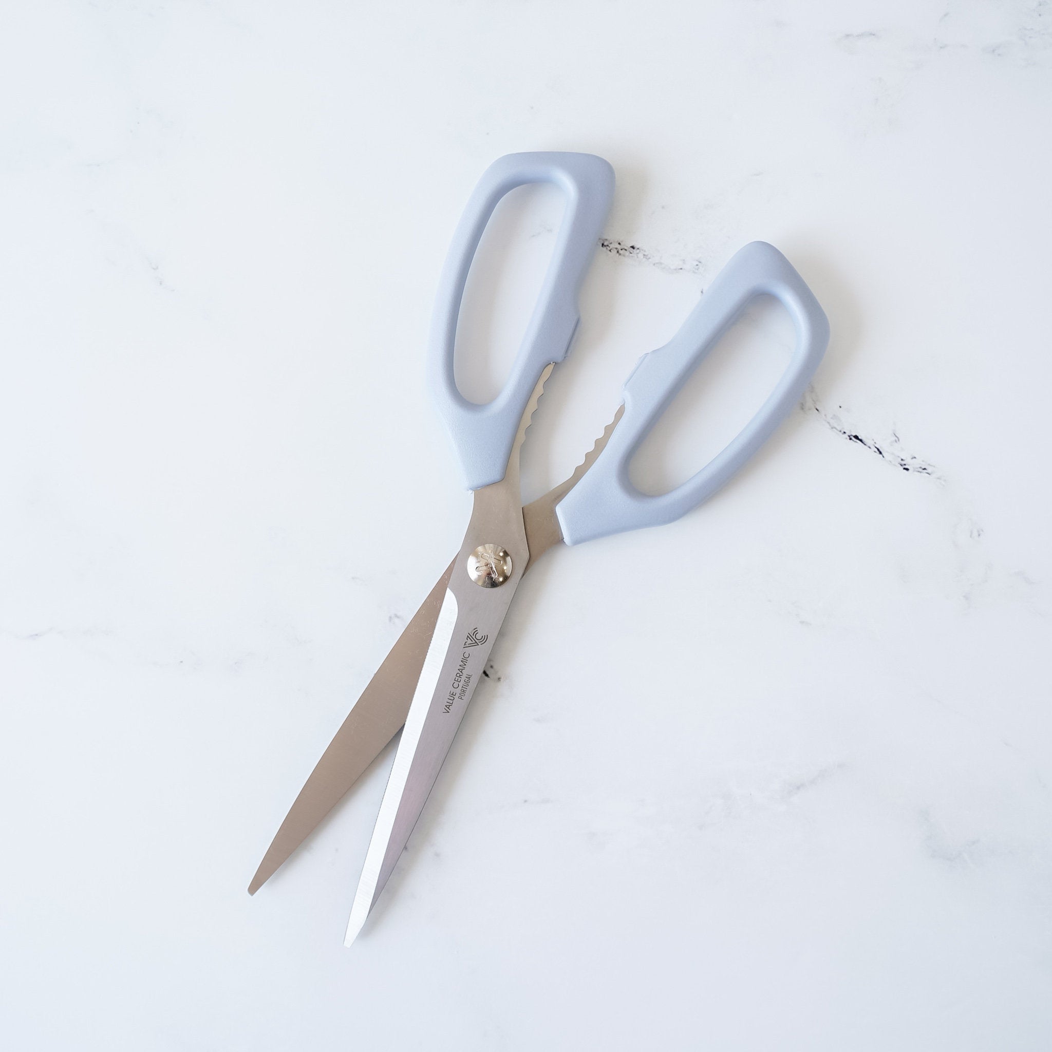 A pair of blue kitchen scissors with a serrated blade. 