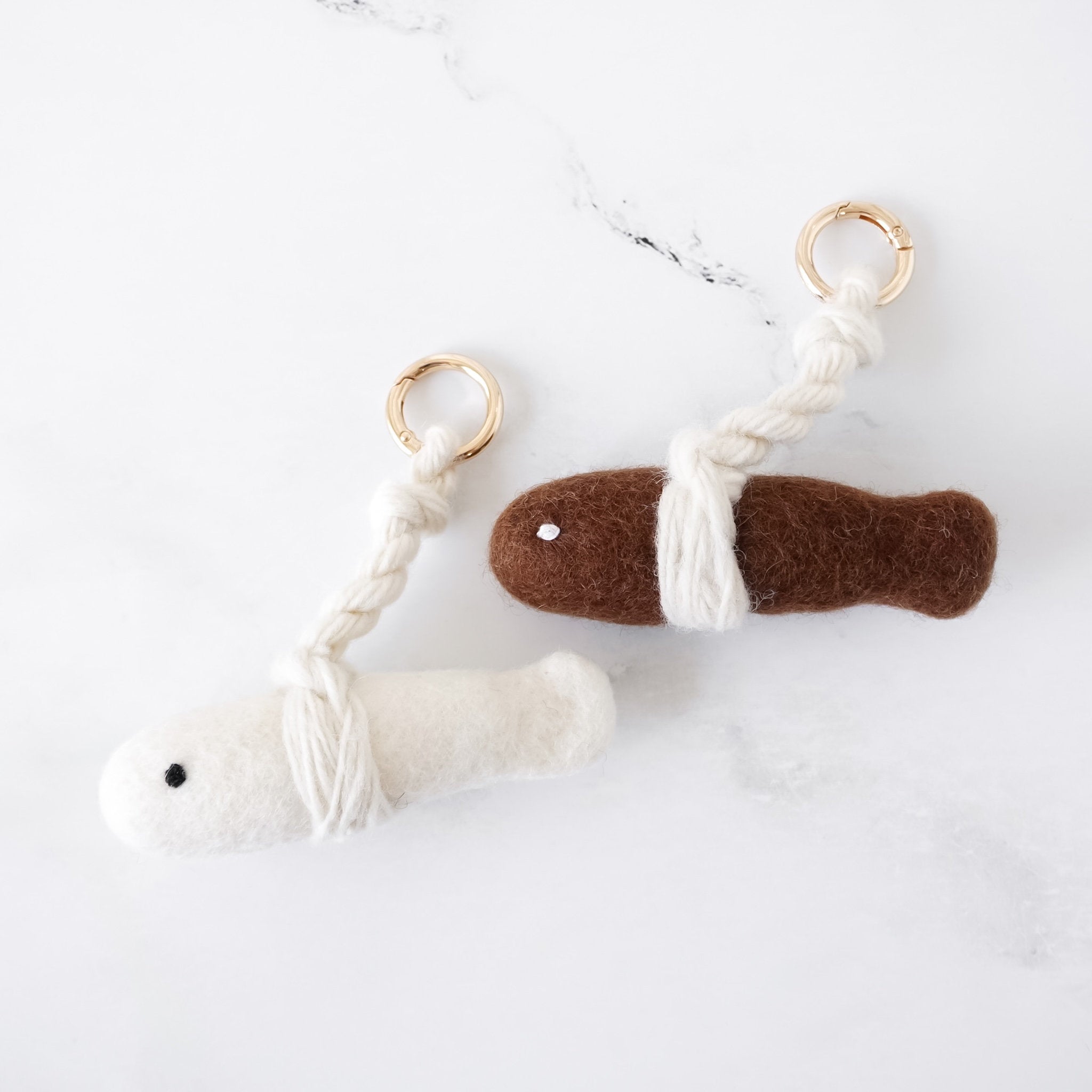 Two keychains, one white and one brown with a white string, on a light background.
