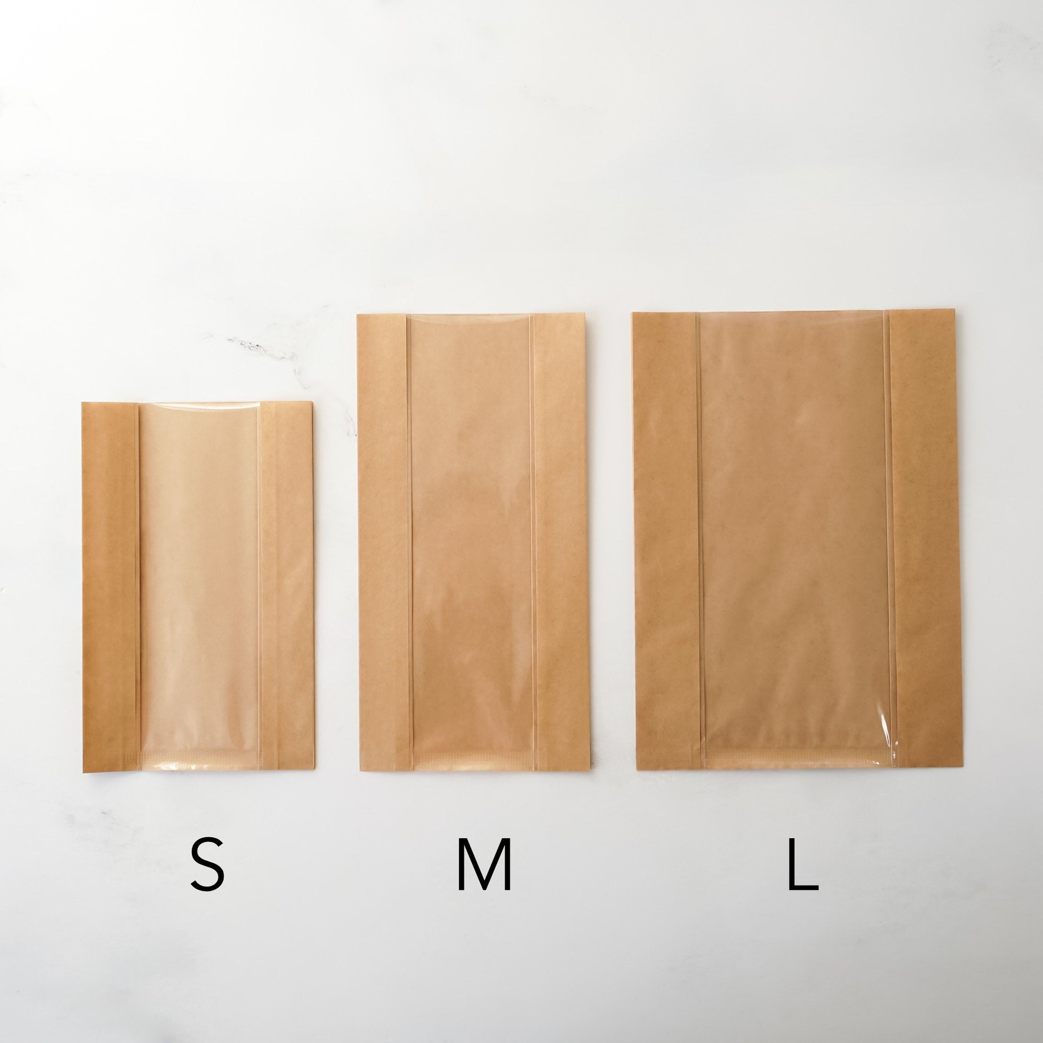 Three brown paper bags labeled S, M, and L on a white background