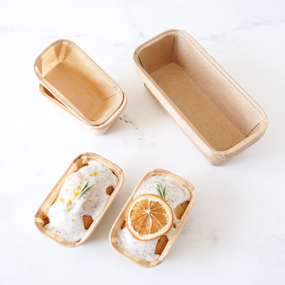 Small loaf pans with baked goods on a white surface