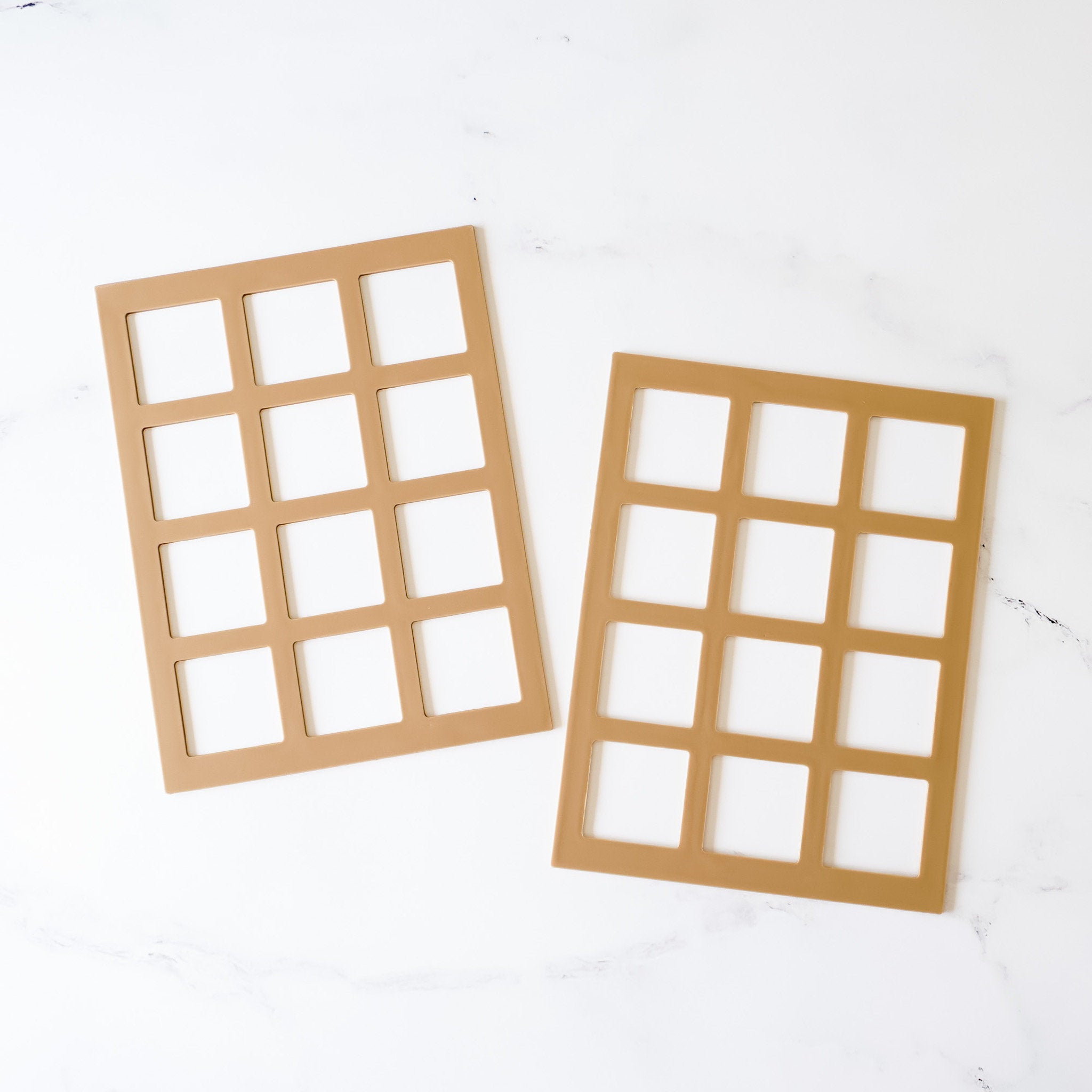 Two silicone cookie stencils with shapes for squares, laid out on a white surface.