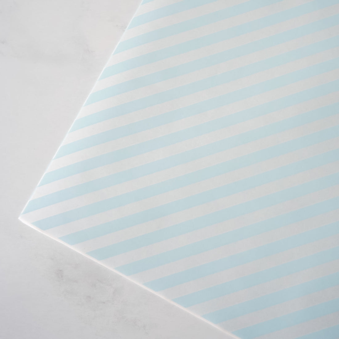 Striped deli paper with light blue and white stripes on a gray background