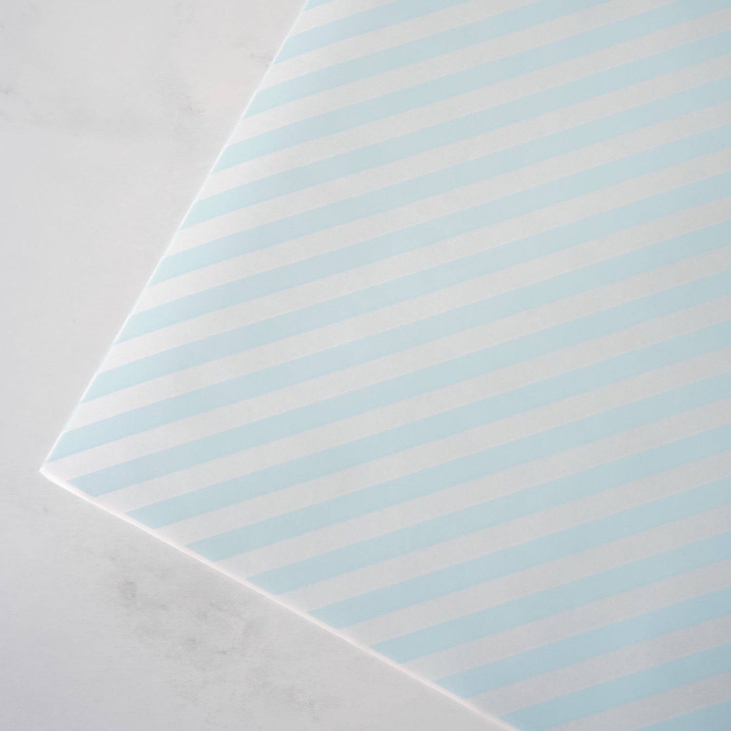 Striped deli paper with light blue and white stripes on a gray background