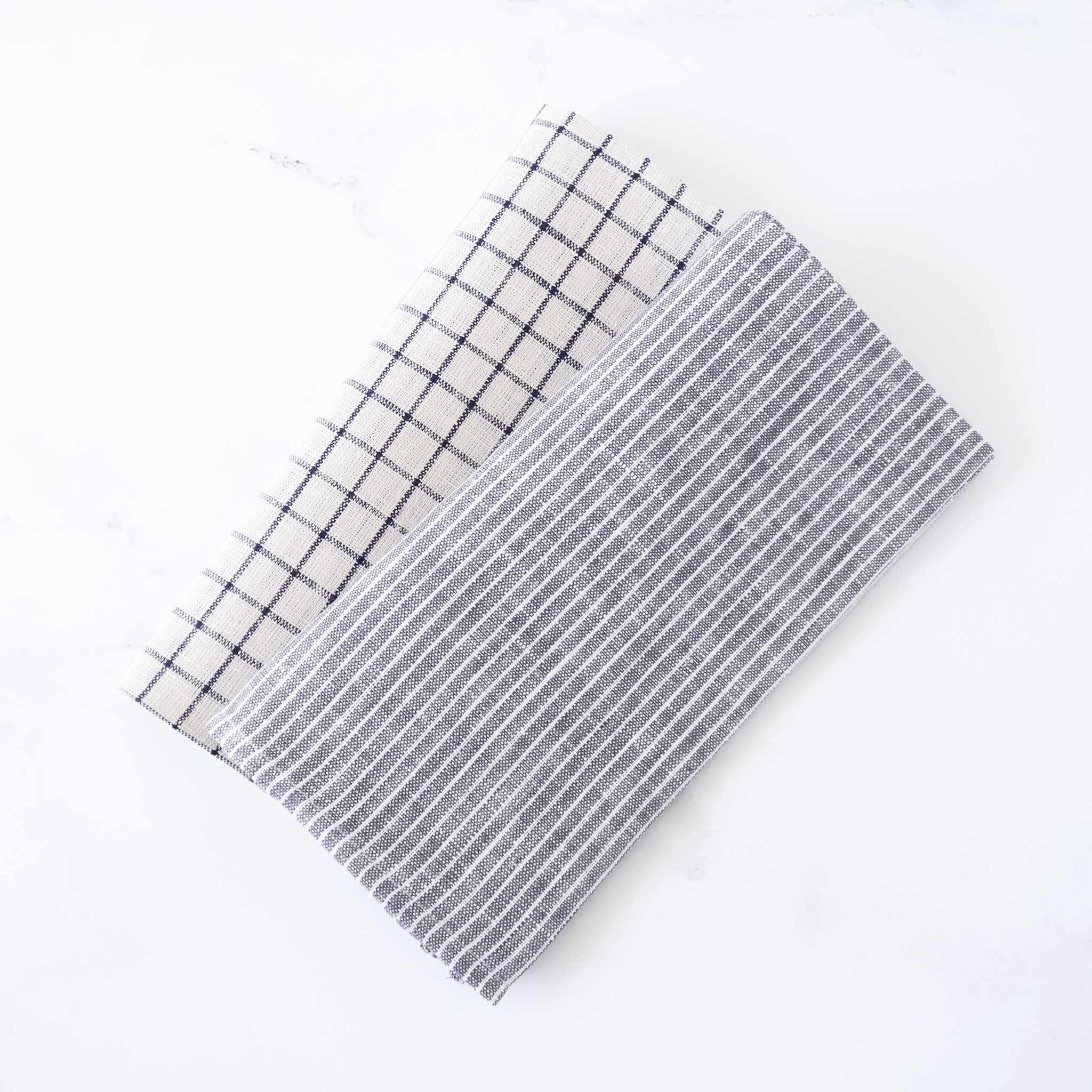 Two rectangular fabric napkins with grid patterns on a white background