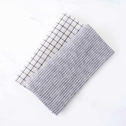 Two rectangular fabric napkins with grid patterns on a white background