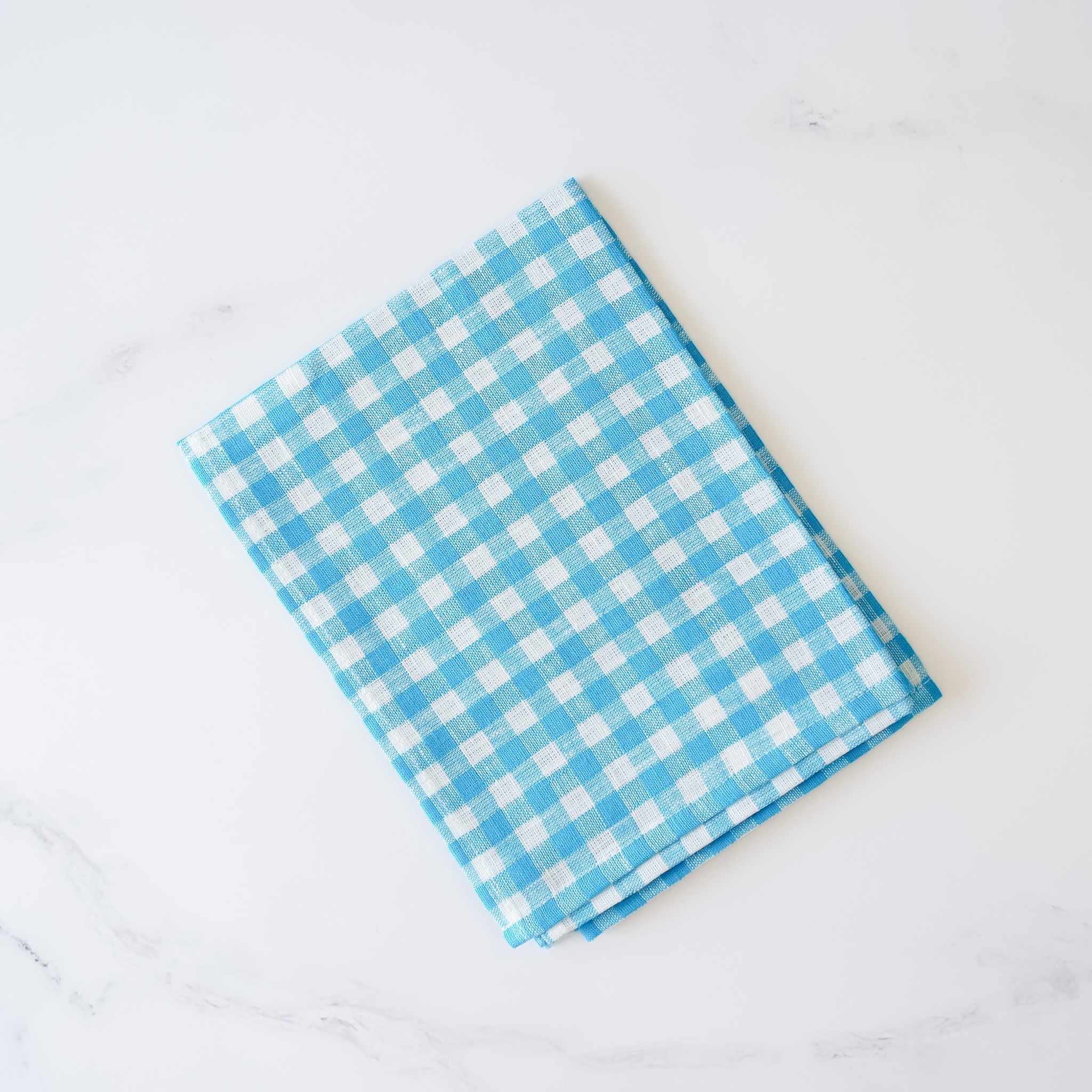 A blue and white checkered linen dishcloth laid out on a flat surface.
