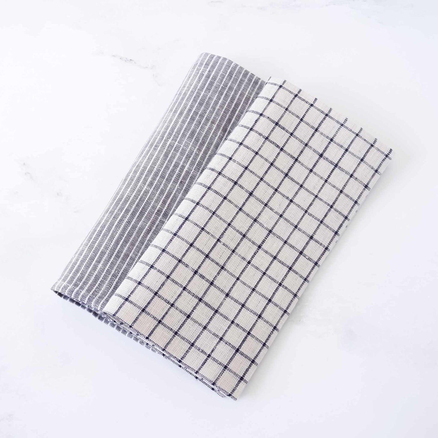 Two folded checkered linen napkins, one gray and white, one black and white, on a white background.