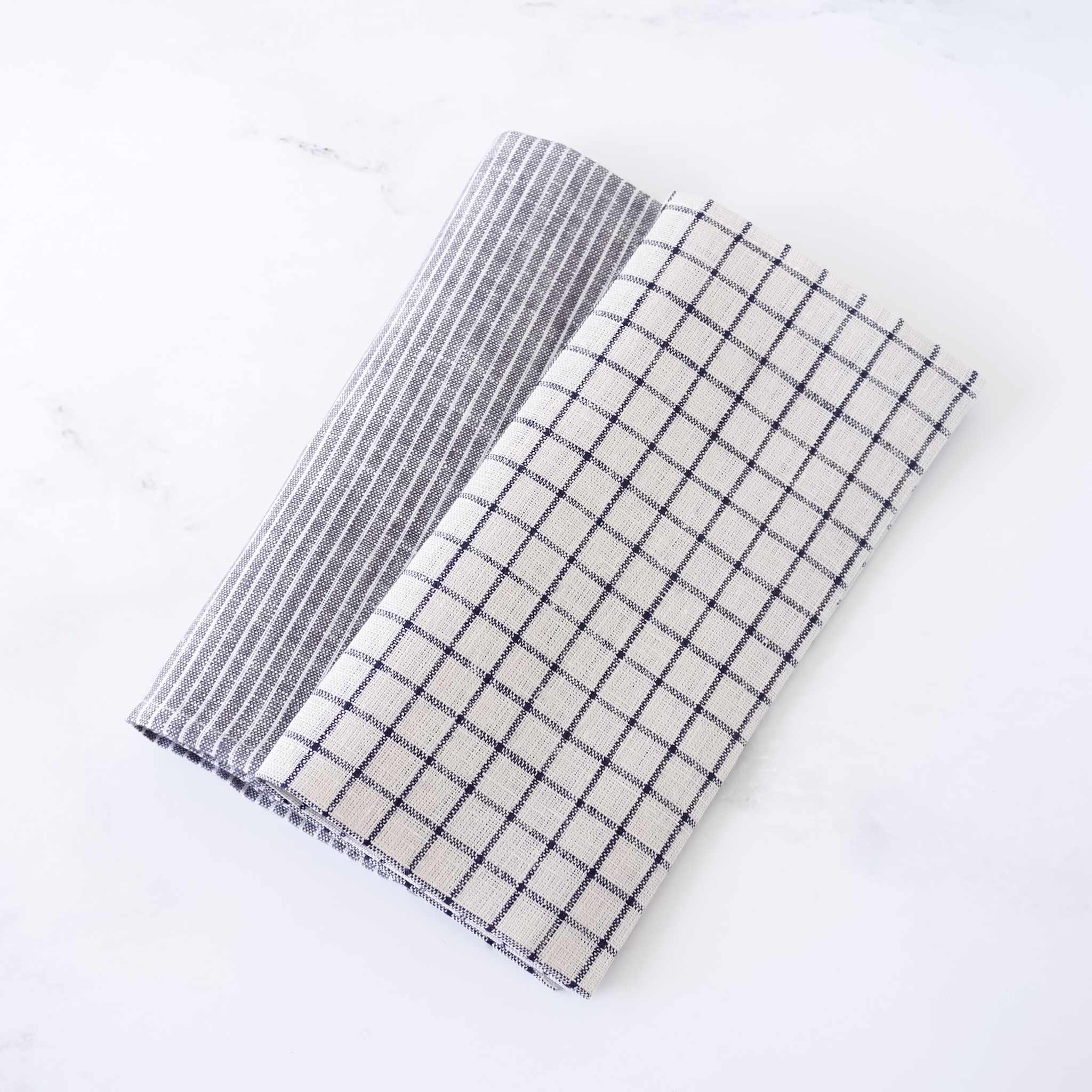 Two folded checkered linen napkins, one gray and white, one black and white, on a white background.
