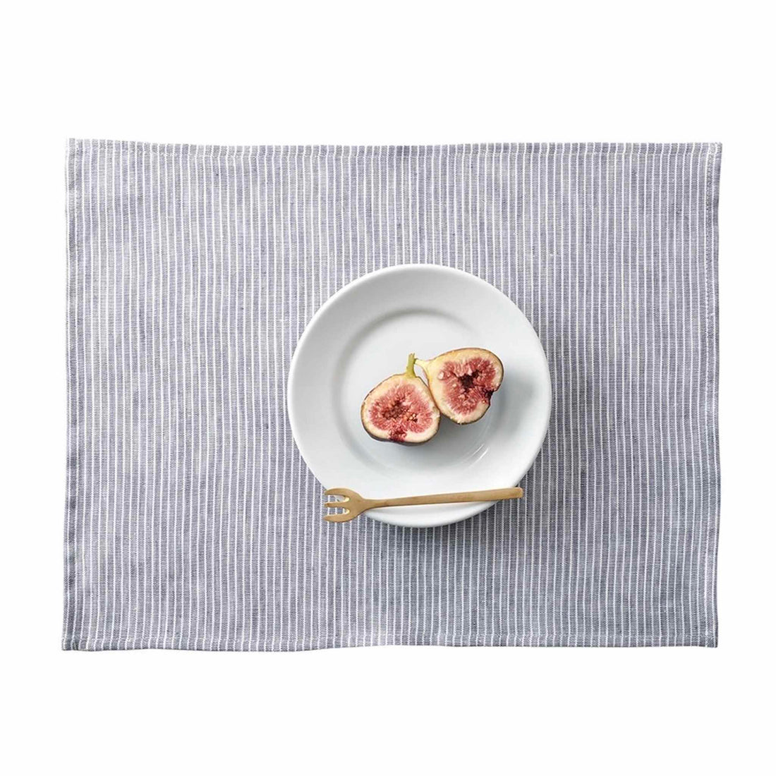 White plate with figs on a gray striped placemat