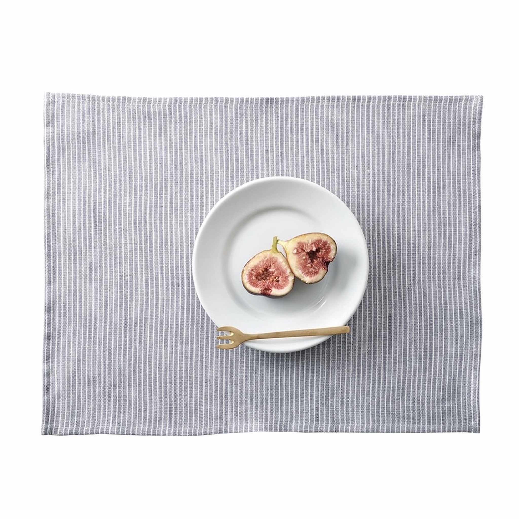 White plate with figs on a gray striped placemat